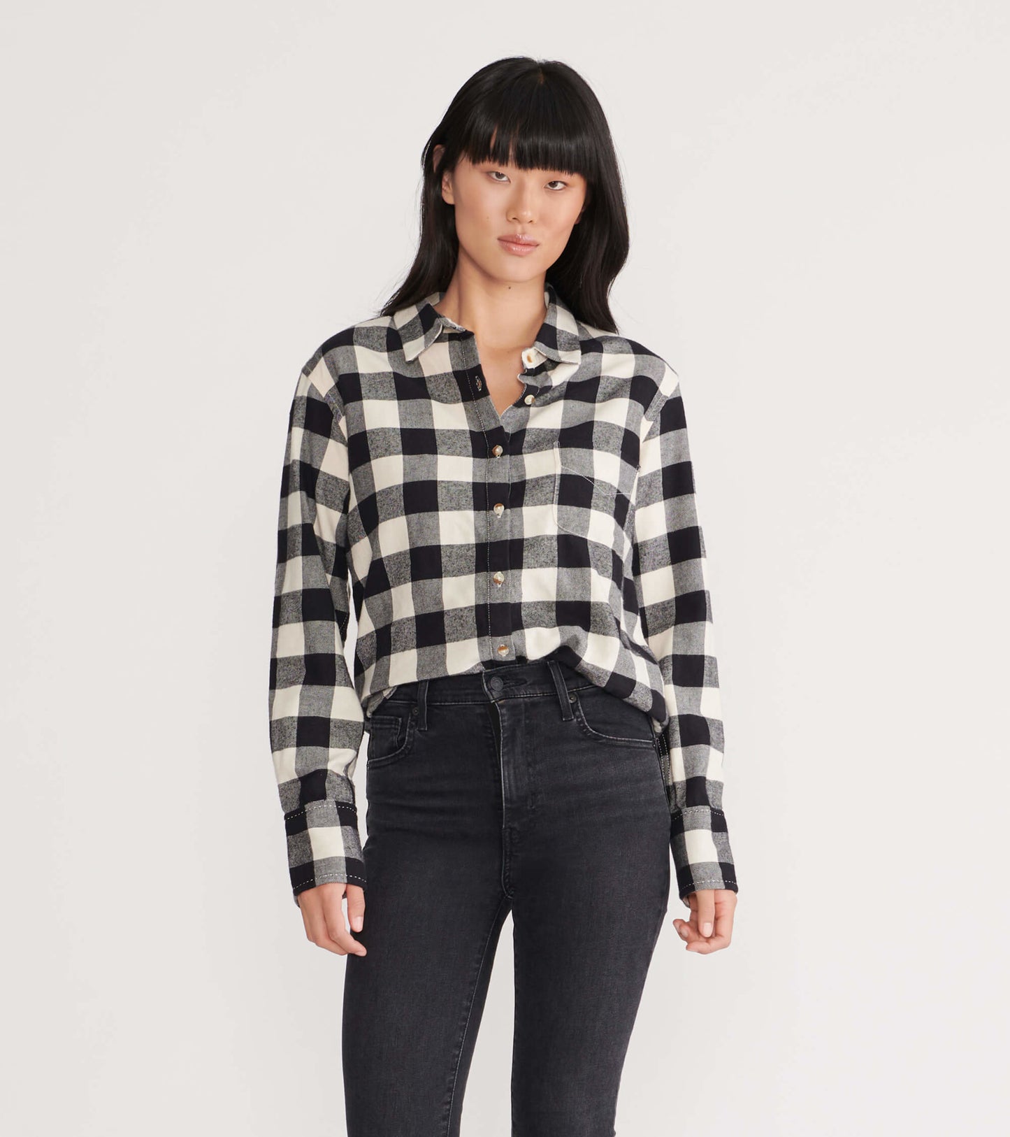 Black and white plaid flannel shirt with a button-up front and long sleeves, styled with high-waisted black jeans.