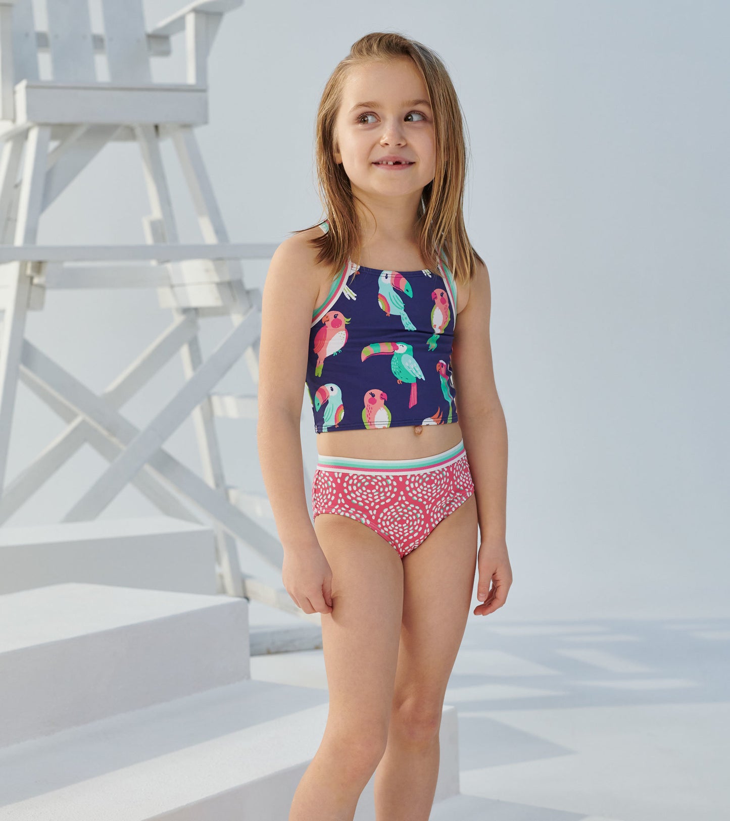 Tankini set featuring a navy top with colorful tropical birds and a pink patterned bottom, ideal for summer wear.