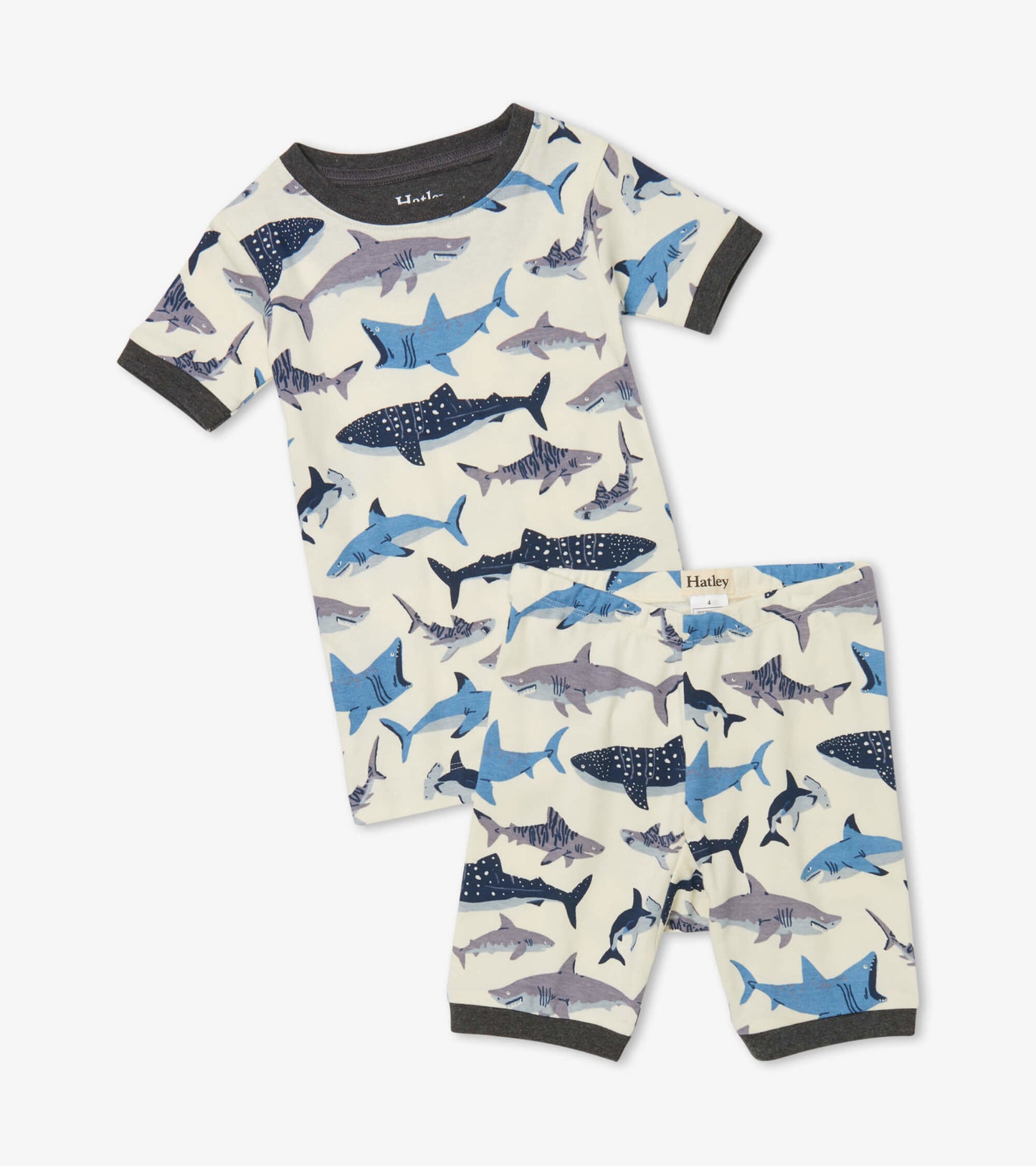 Short pajama set in cream with blue shark patterns, featuring a short-sleeve top and matching shorts.