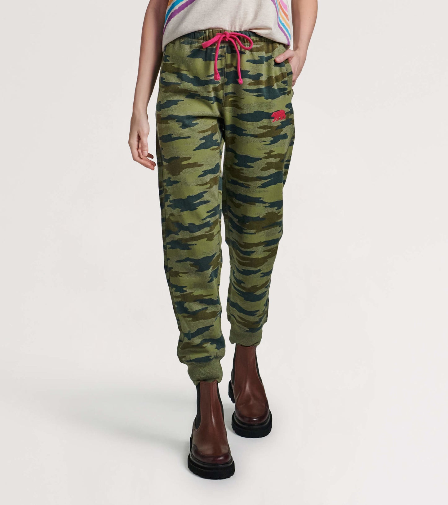Green camouflage joggers with a relaxed fit, featuring a pink drawstring and side pockets, styled with ankle boots.