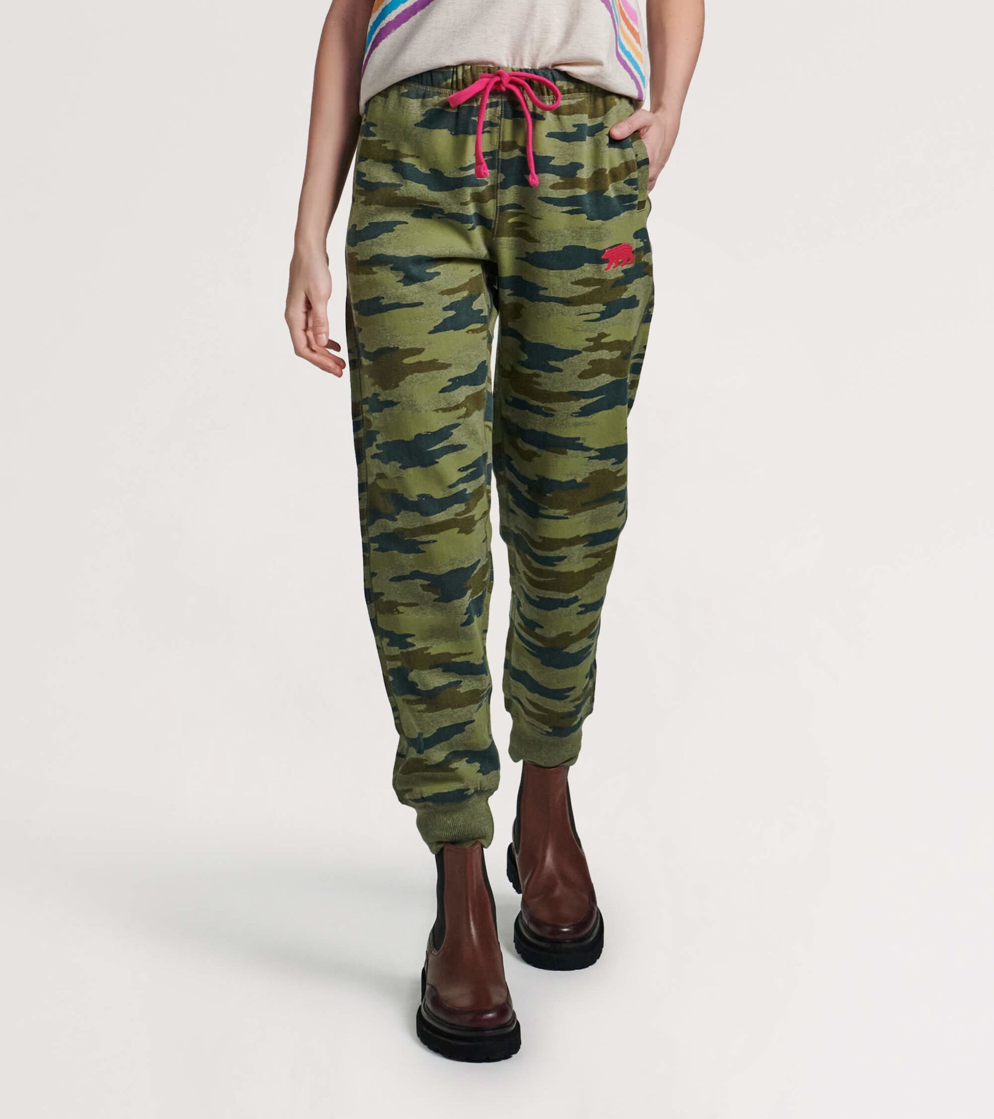 Green camouflage joggers with a relaxed fit, featuring a pink drawstring and side pockets, styled with ankle boots.
