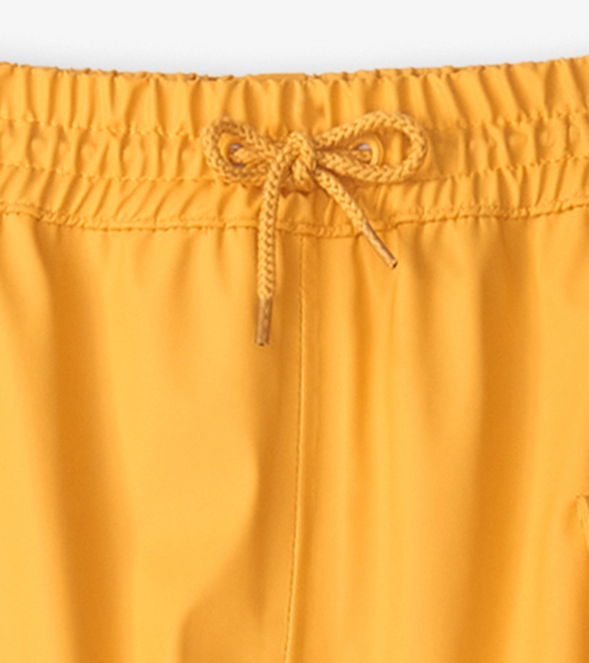 Yellow kids' rain pants featuring an elastic waistband with a drawstring for adjustable fit.