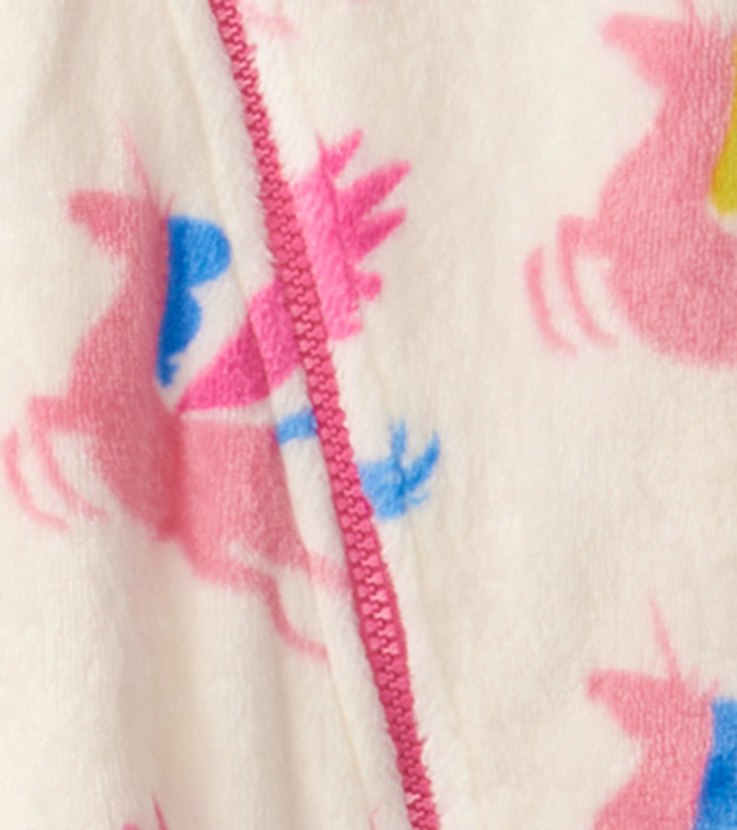 Cream fleece suit featuring colorful unicorn patterns, with a pink zipper and soft texture, suitable for babies.
