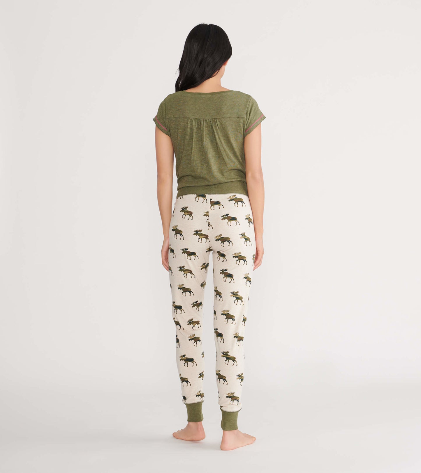 Women's sleep leggings in cream with a moose pattern and green cuffs, shown from the back.
