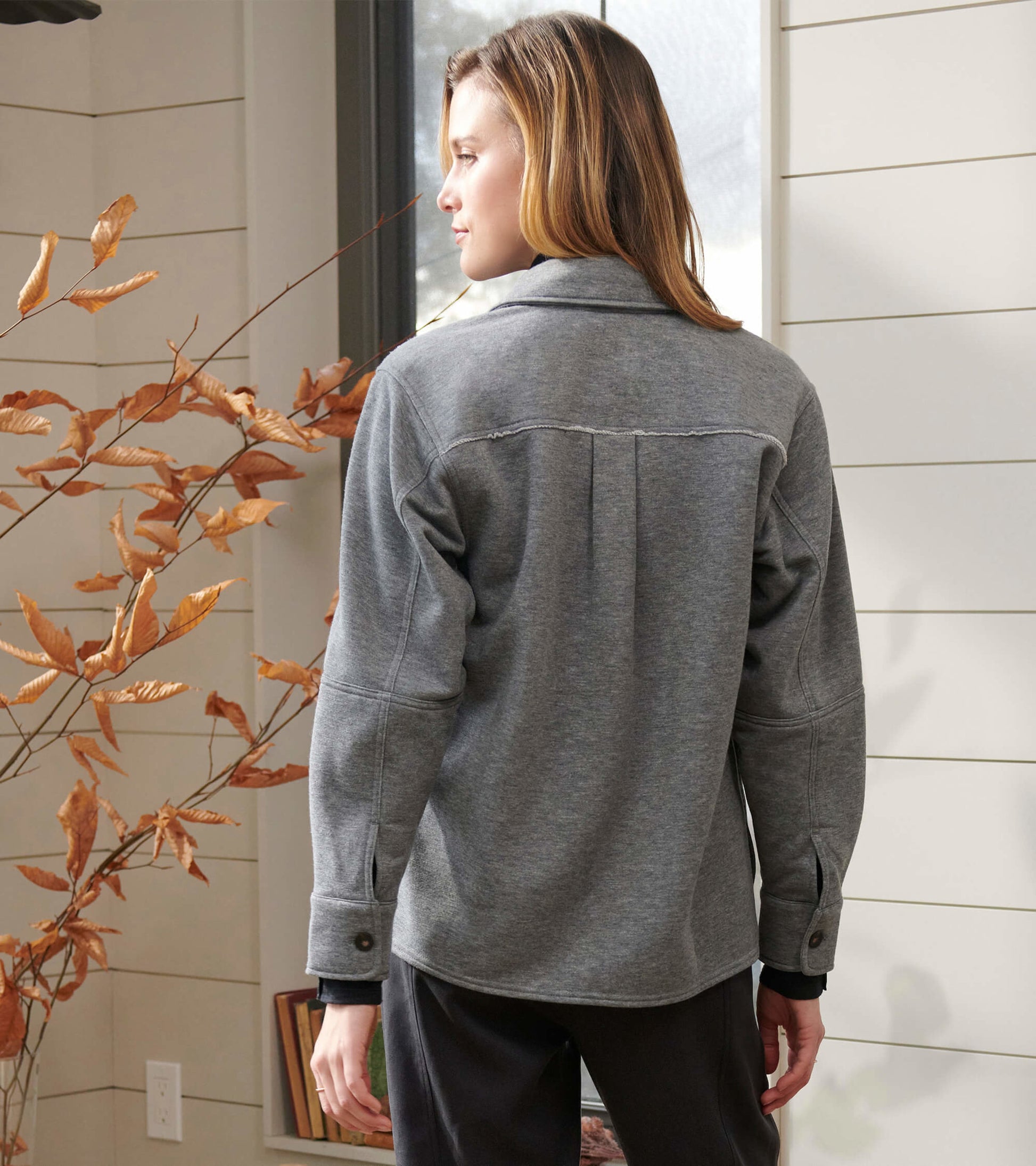 Charcoal melange relaxed blazer with a collar and buttoned cuffs, shown from the back in a cozy indoor setting.