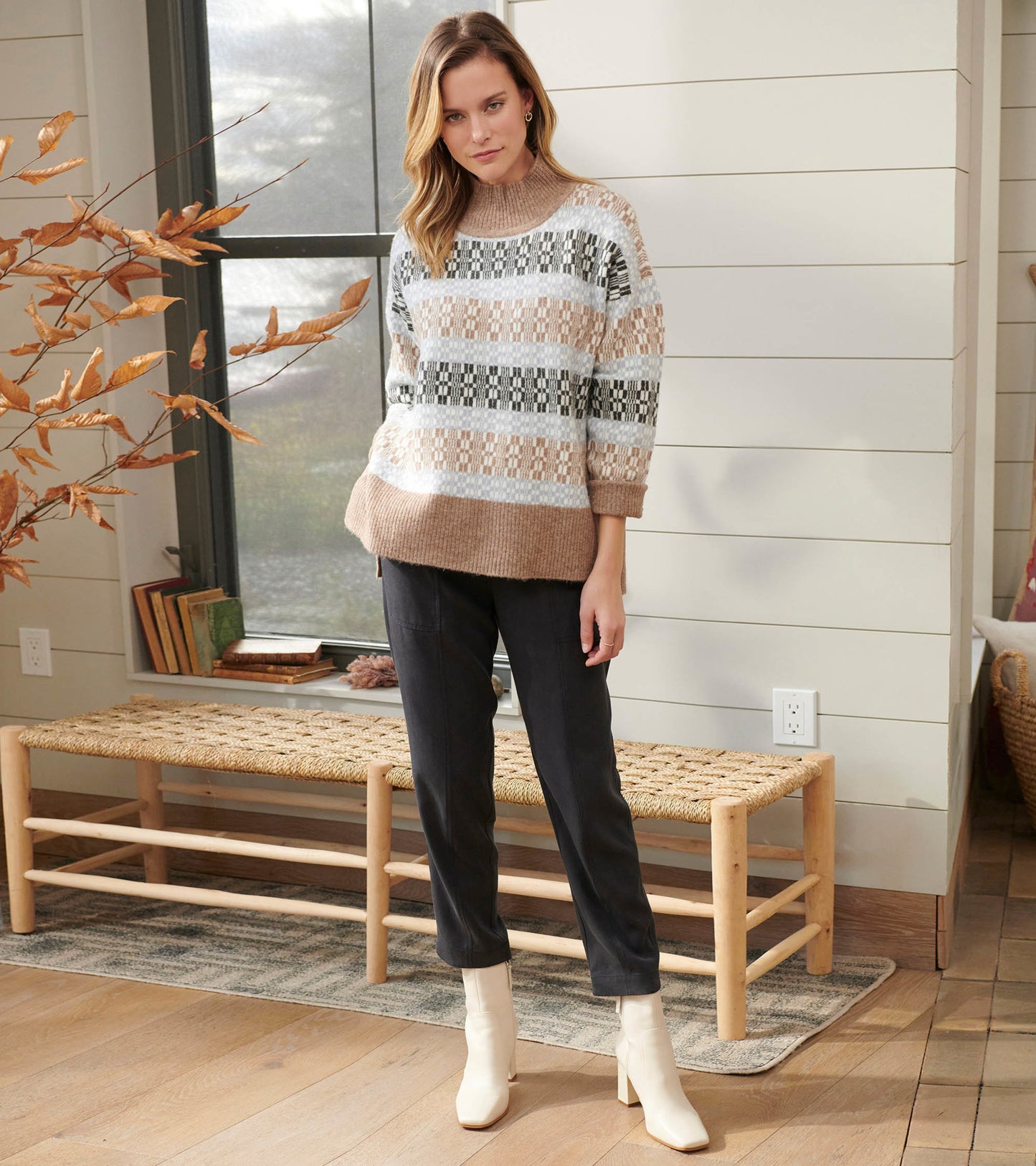 Mock neck sweater featuring a celestial plaid pattern in beige, gray, and black, paired with dark pants and white boots.