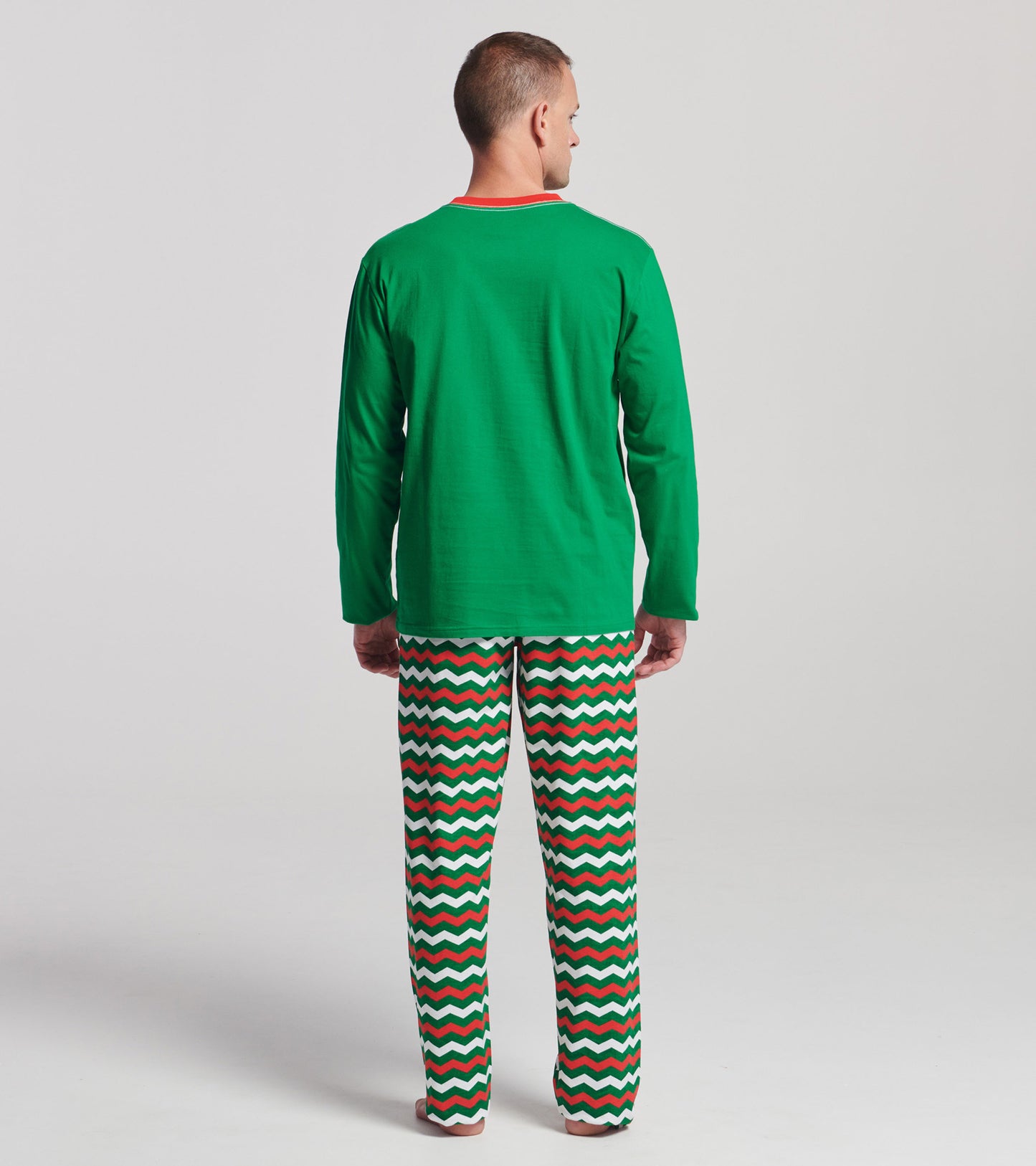Green long sleeve t-shirt with a red collar, worn with patterned pajama pants featuring zigzag stripes in red, green, and wh…