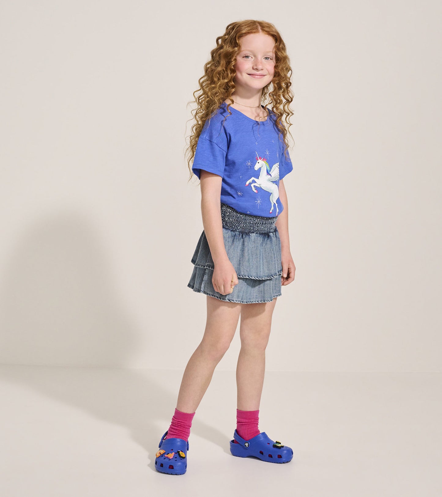 Light blue Tencel smocked skirt with tiered layers, styled with a graphic tee and colorful clogs.
