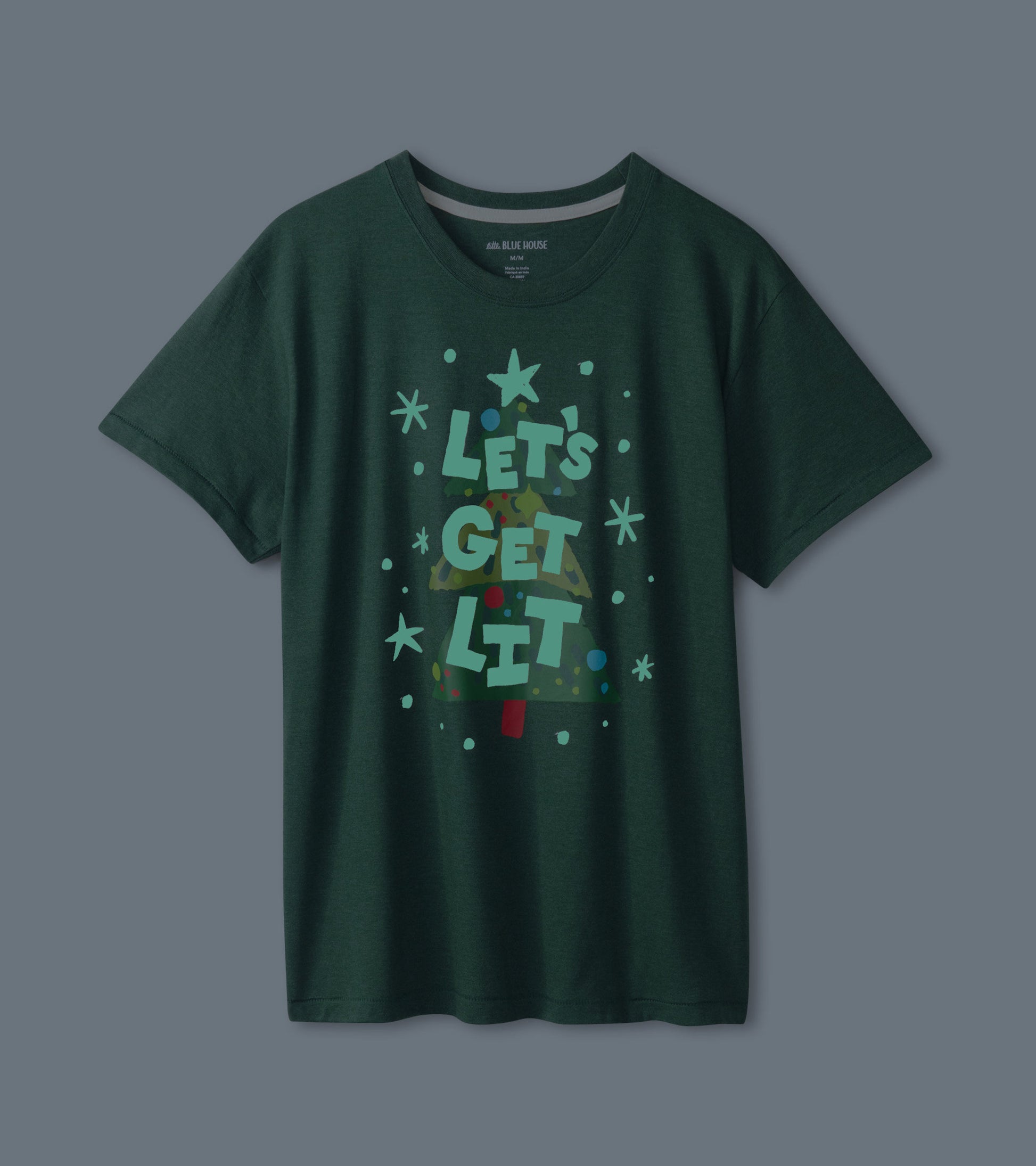 Green short-sleeve t-shirt featuring a festive Christmas tree graphic with colorful ornaments and text.