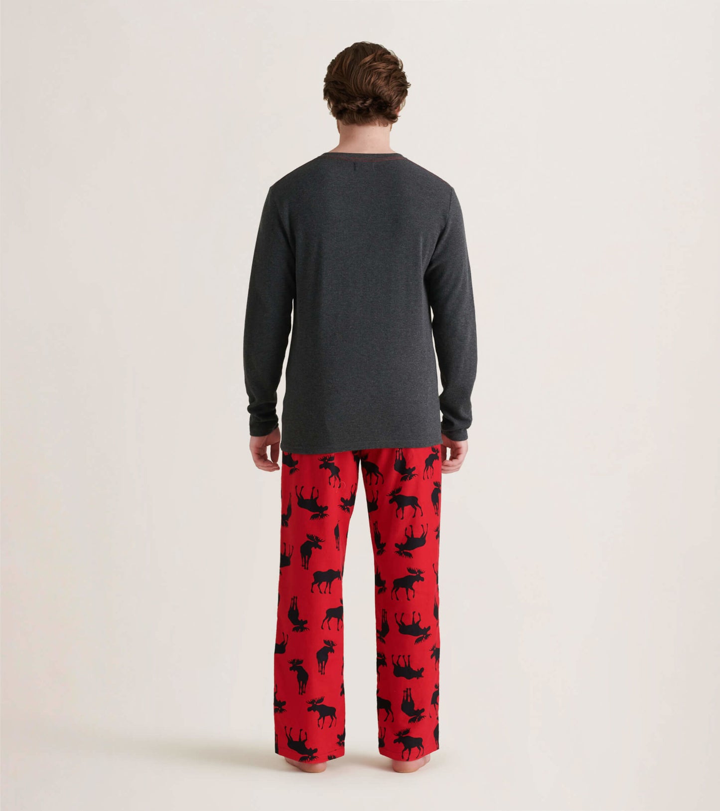 Red flannel pajama pants featuring a moose pattern, worn with a long-sleeve gray top, viewed from the back.