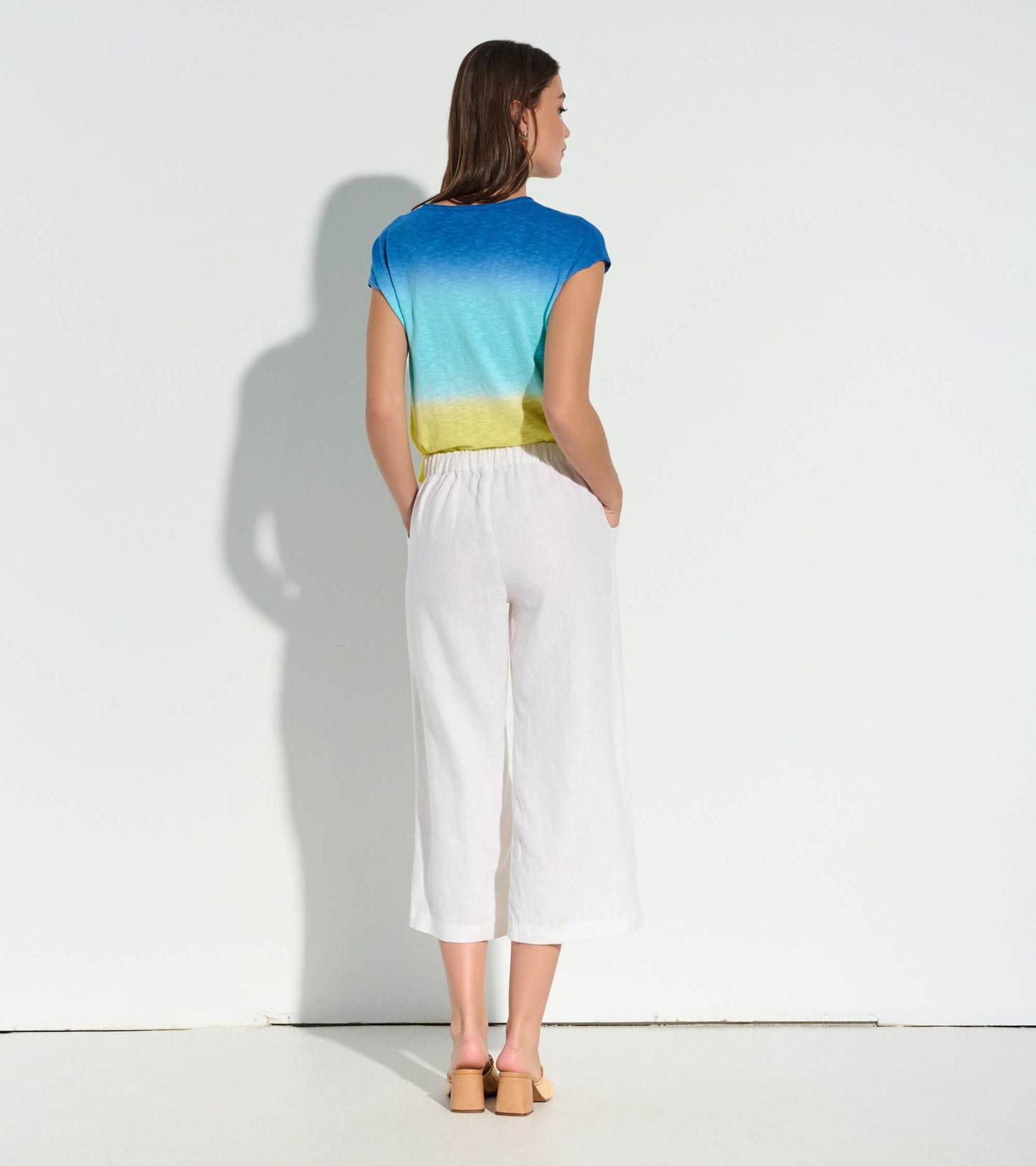 Cropped wide leg pants in white, featuring a relaxed fit and elastic waistband, styled with a colorful top.