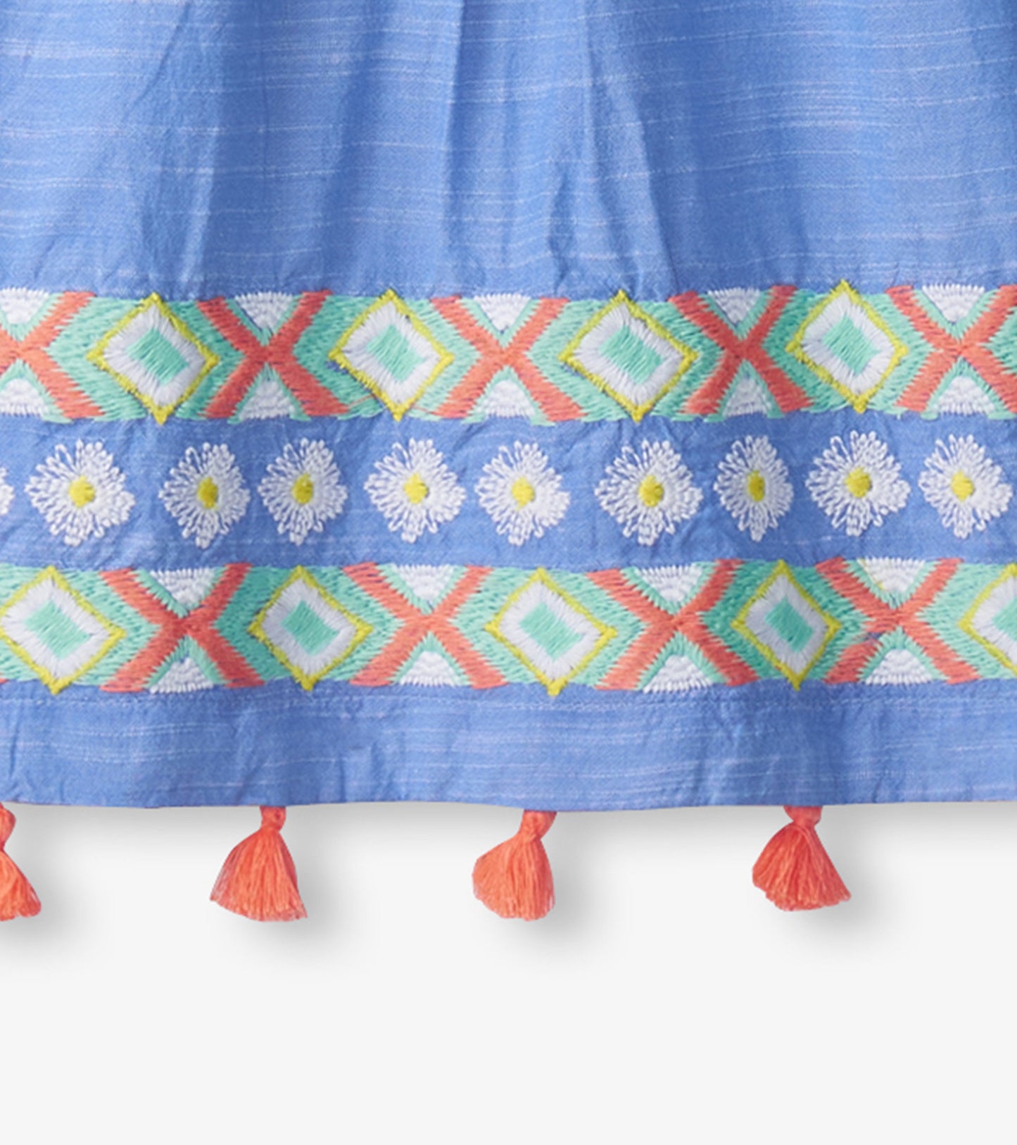 Light blue chambray dress featuring colorful embroidered patterns and tassel accents at the hem.