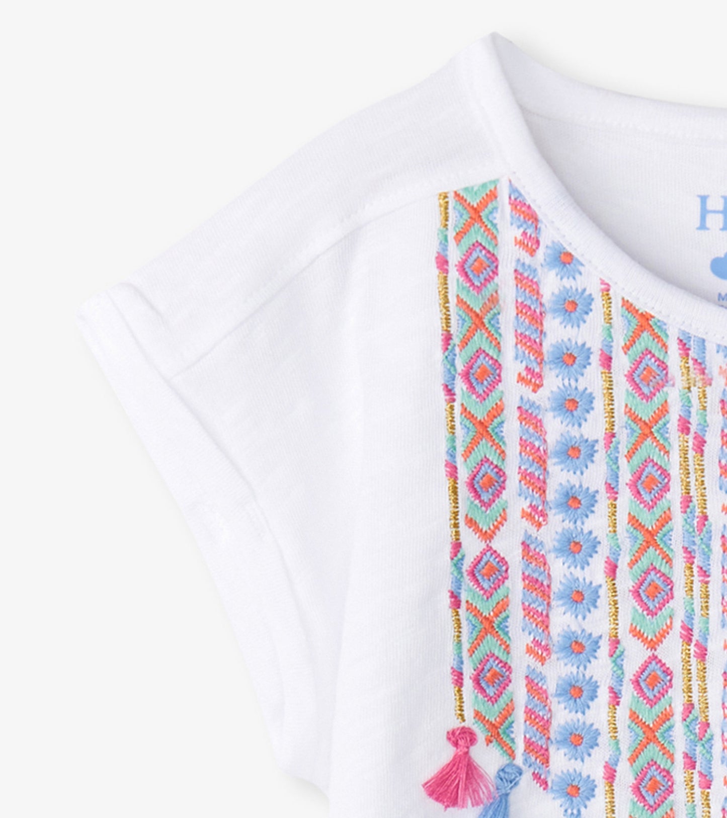 White relaxed t-shirt featuring colorful embroidered patterns and tassels on the front.