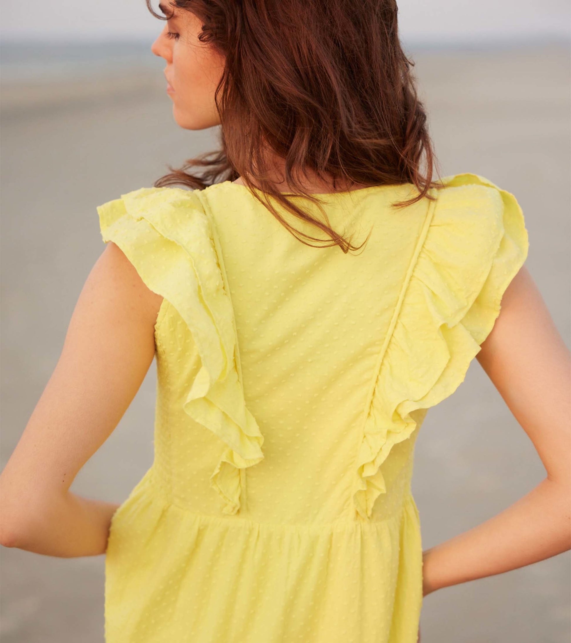 Yellow Swiss dot midi dress featuring ruffled sleeves and a relaxed fit, shown from the back.