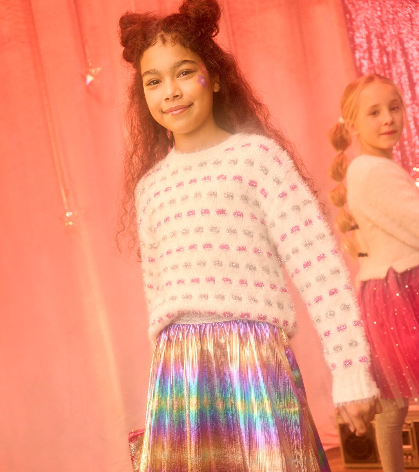 White sweater tunic with pink and silver polka dots, paired with a shiny, iridescent skirt.