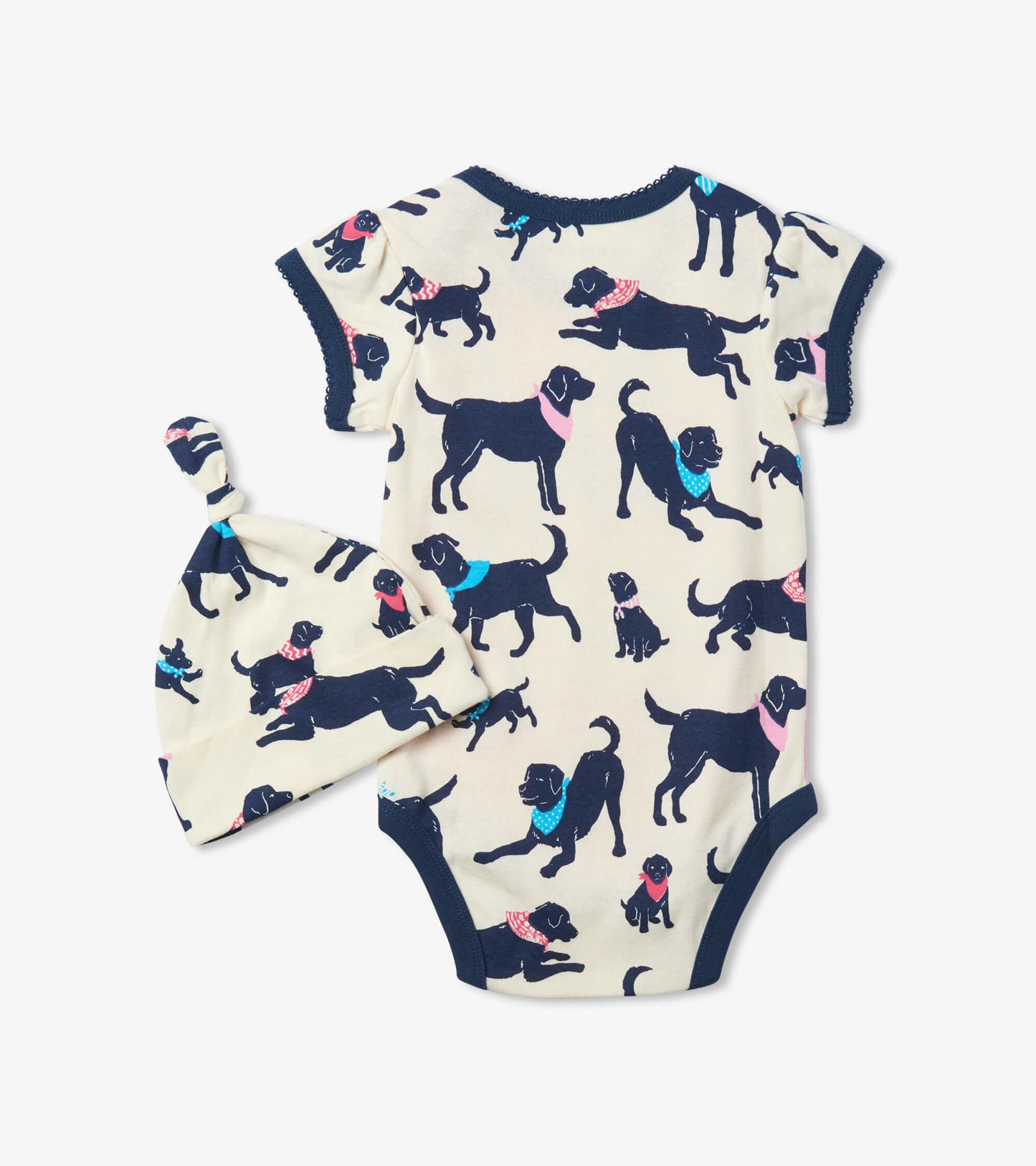 Cream baby bodysuit with playful black dog prints and a matching knotted hat, featuring short sleeves and a round neckline.