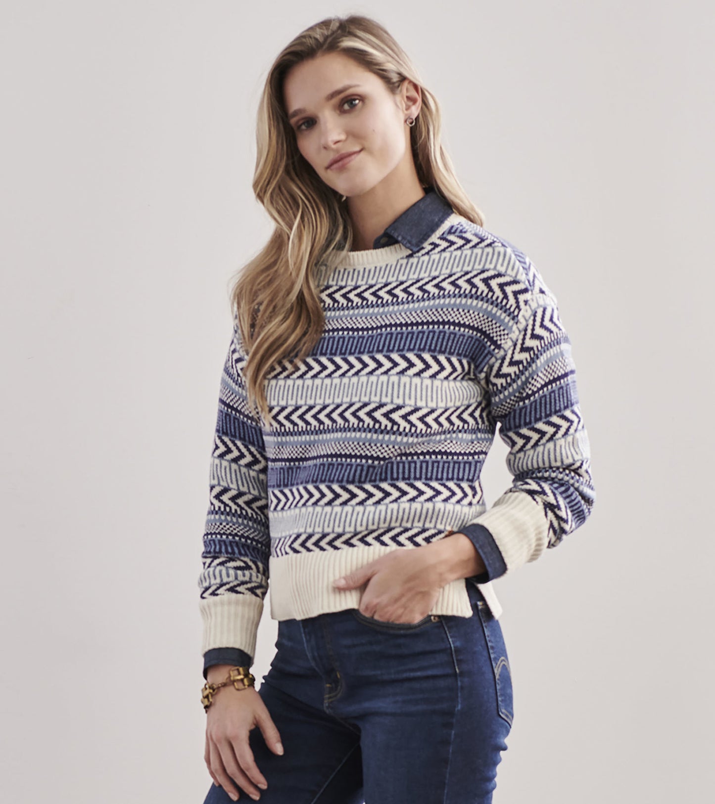 Blue and cream patterned sweater with a crew neck and ribbed hem, styled with a denim shirt underneath.