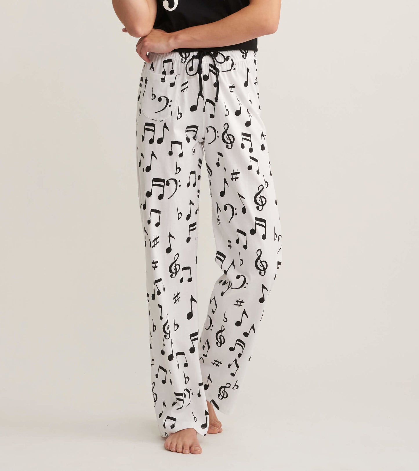 White cotton pajama pants featuring a black musical note pattern, with an elastic waistband and relaxed fit.