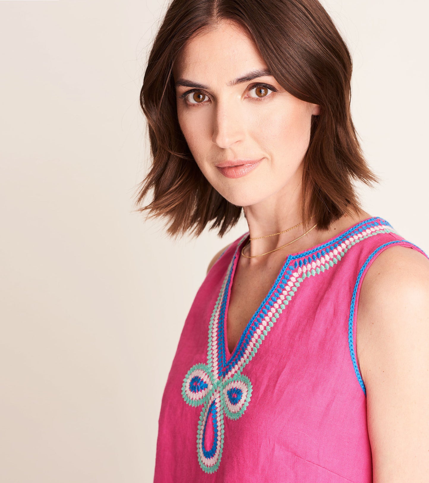 Fuchsia sheath dress featuring a decorative embroidered neckline and sleeveless design.