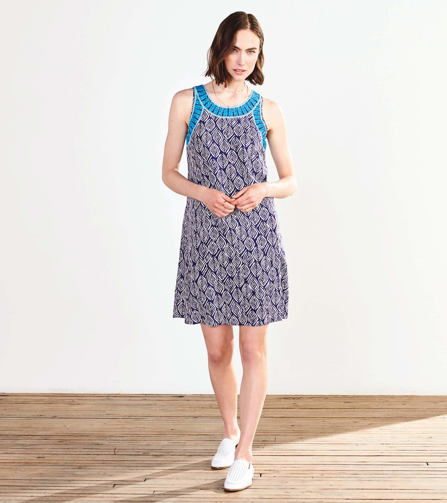 Sleeveless dress featuring a blue patterned bodice and a flowing skirt with a diamond print in navy and white.