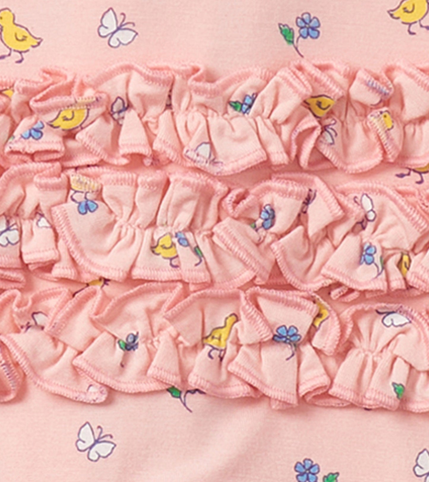 Pink footed sleeper with ruffle detailing, featuring a floral and chick print, suitable for baby girls.