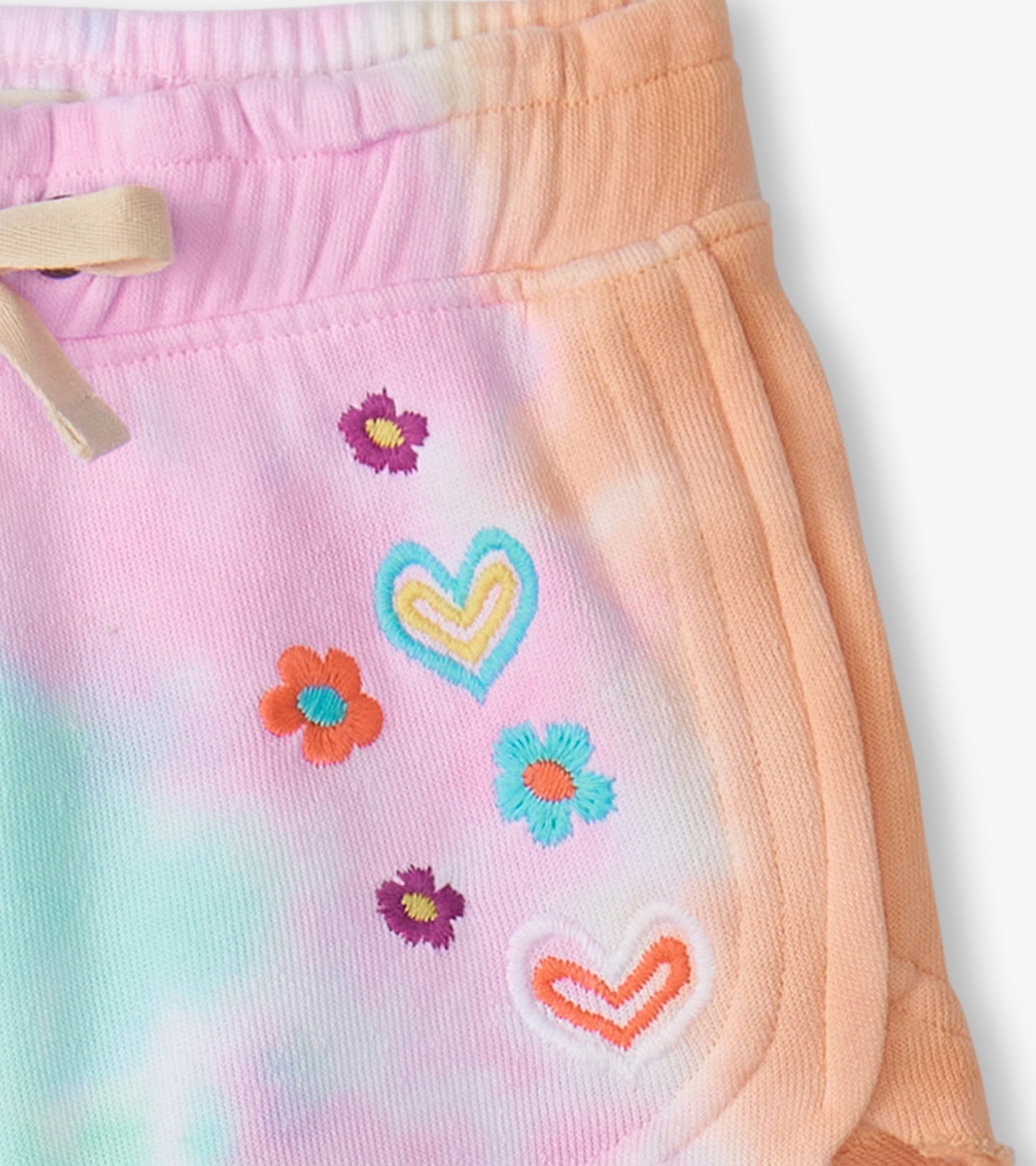 Pink and orange tie-dye pull-on shorts with colorful floral and heart embroidery, featuring an elastic waistband.