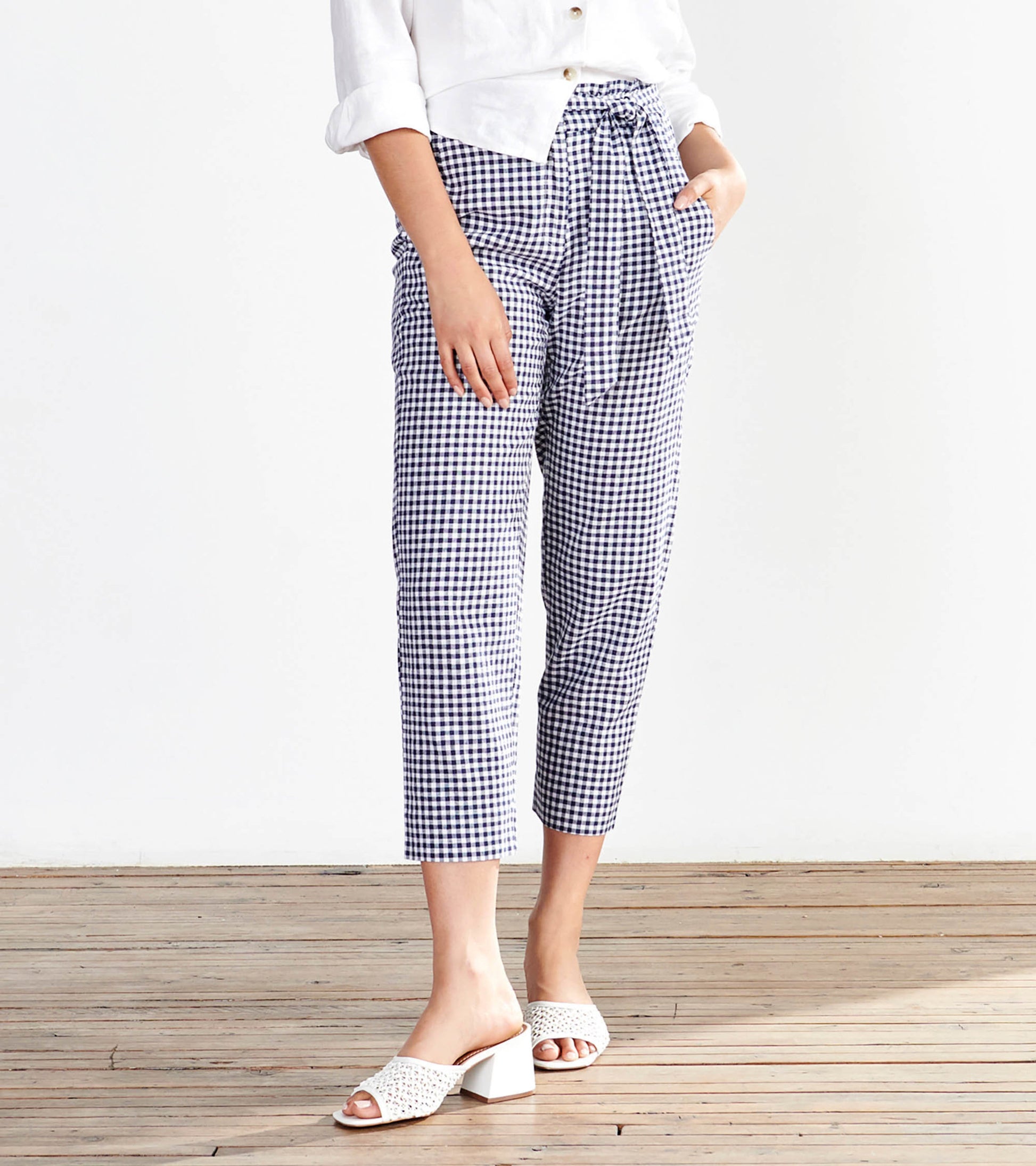 Navy gingham paper bag pants with a tie waist, featuring side pockets and a cropped fit, styled with a white top.