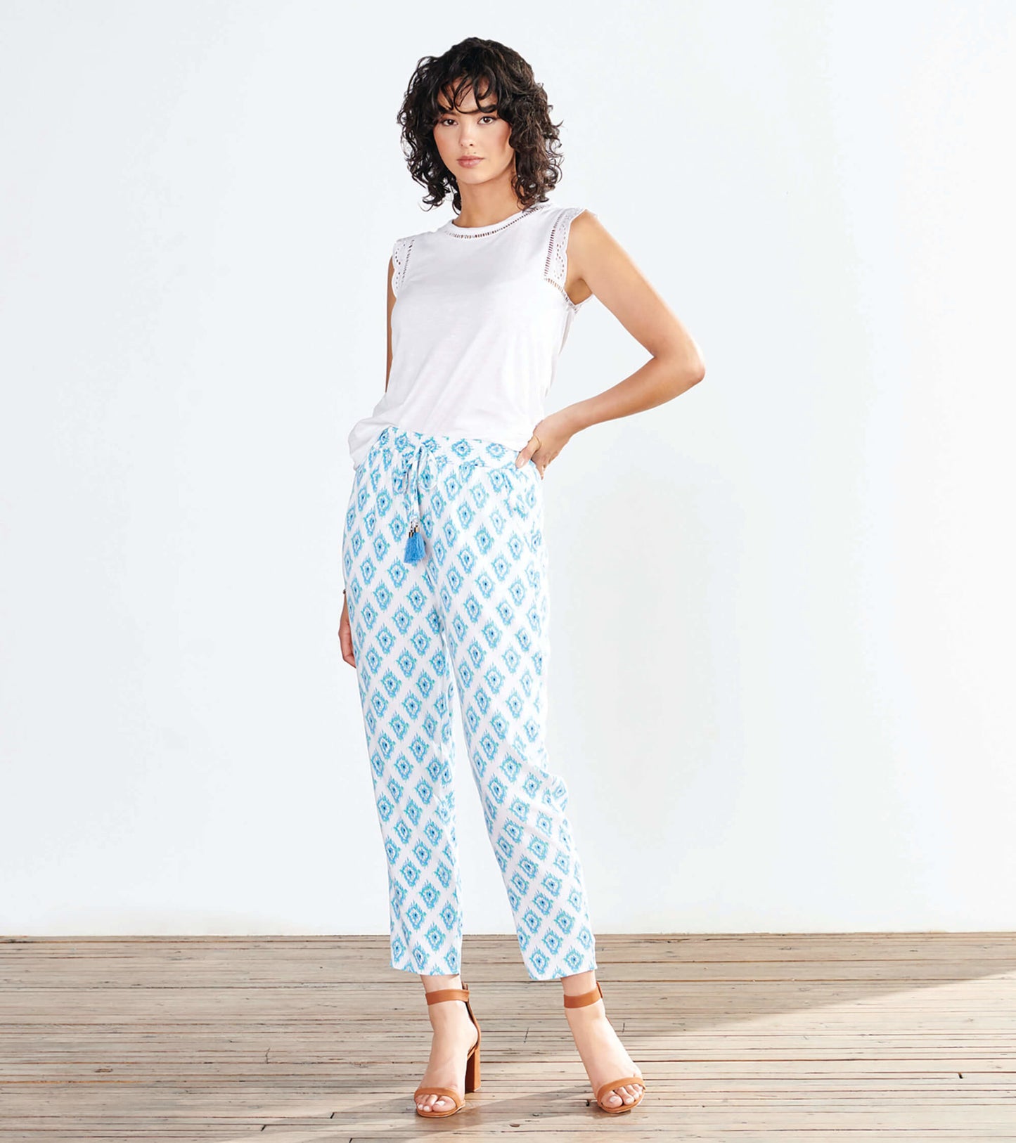 Light blue patterned pants with a drawstring waist, featuring a diamond design, styled with a white top and sandals.