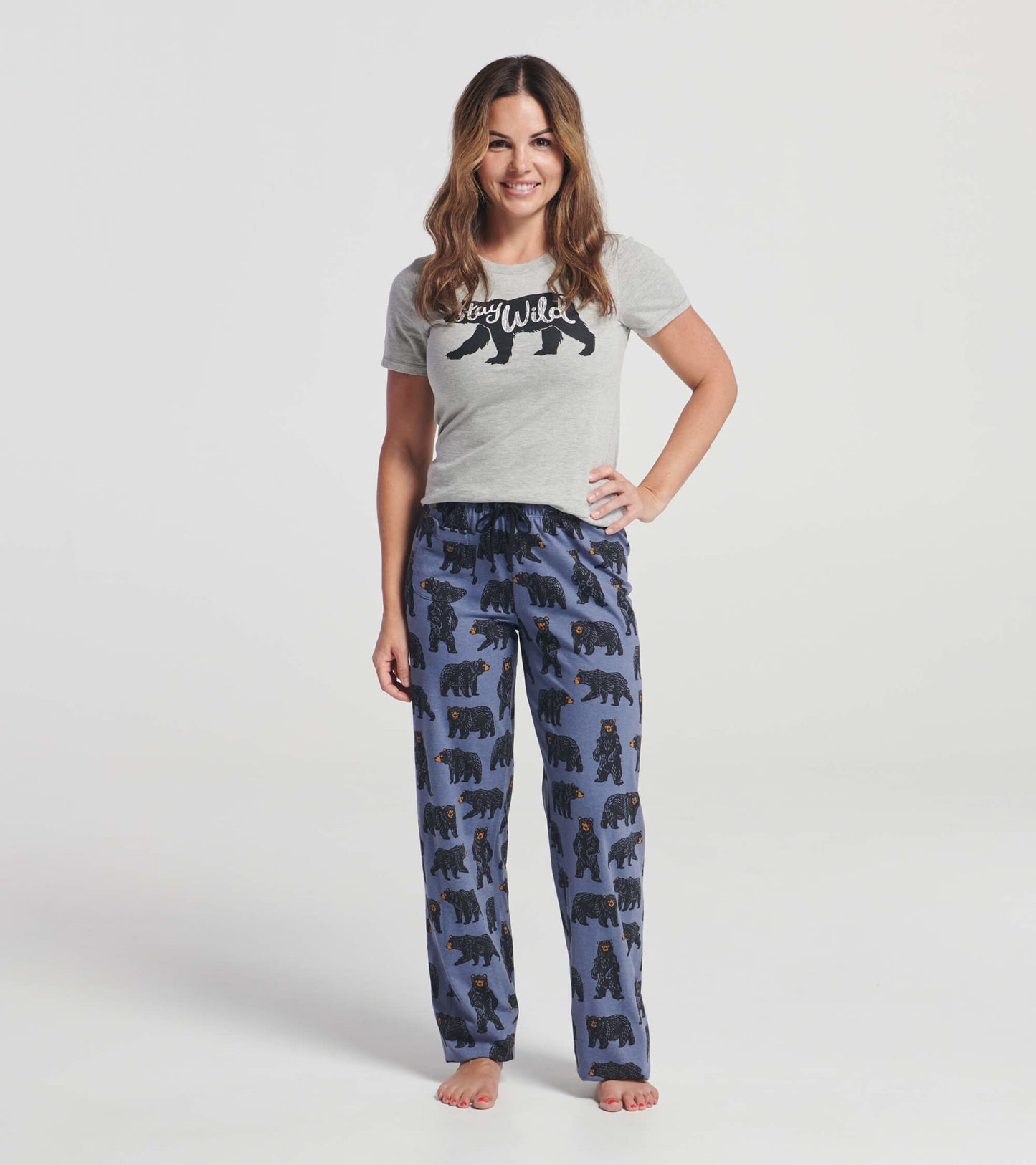 Gray pajama t-shirt with "Stay Wild" text paired with blue pants featuring bear patterns, worn by a smiling woman.
