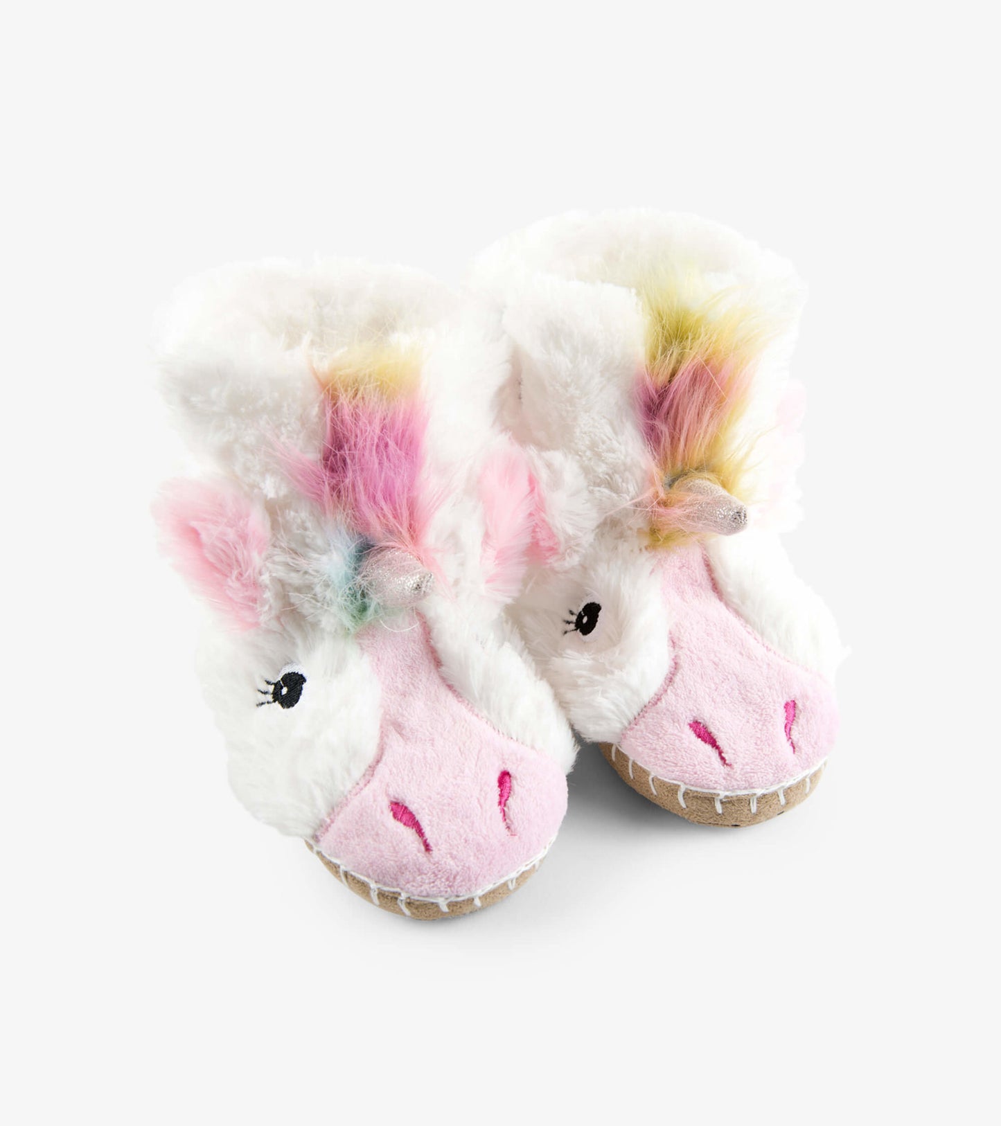 Fuzzy white unicorn slippers with pink accents and colorful mane, designed for kids' comfort and warmth.