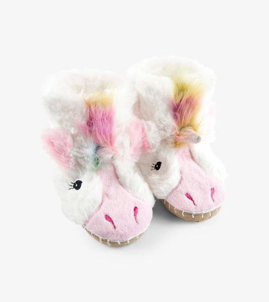 Fuzzy white unicorn slippers with pink accents and colorful mane, designed for kids' comfort and warmth.