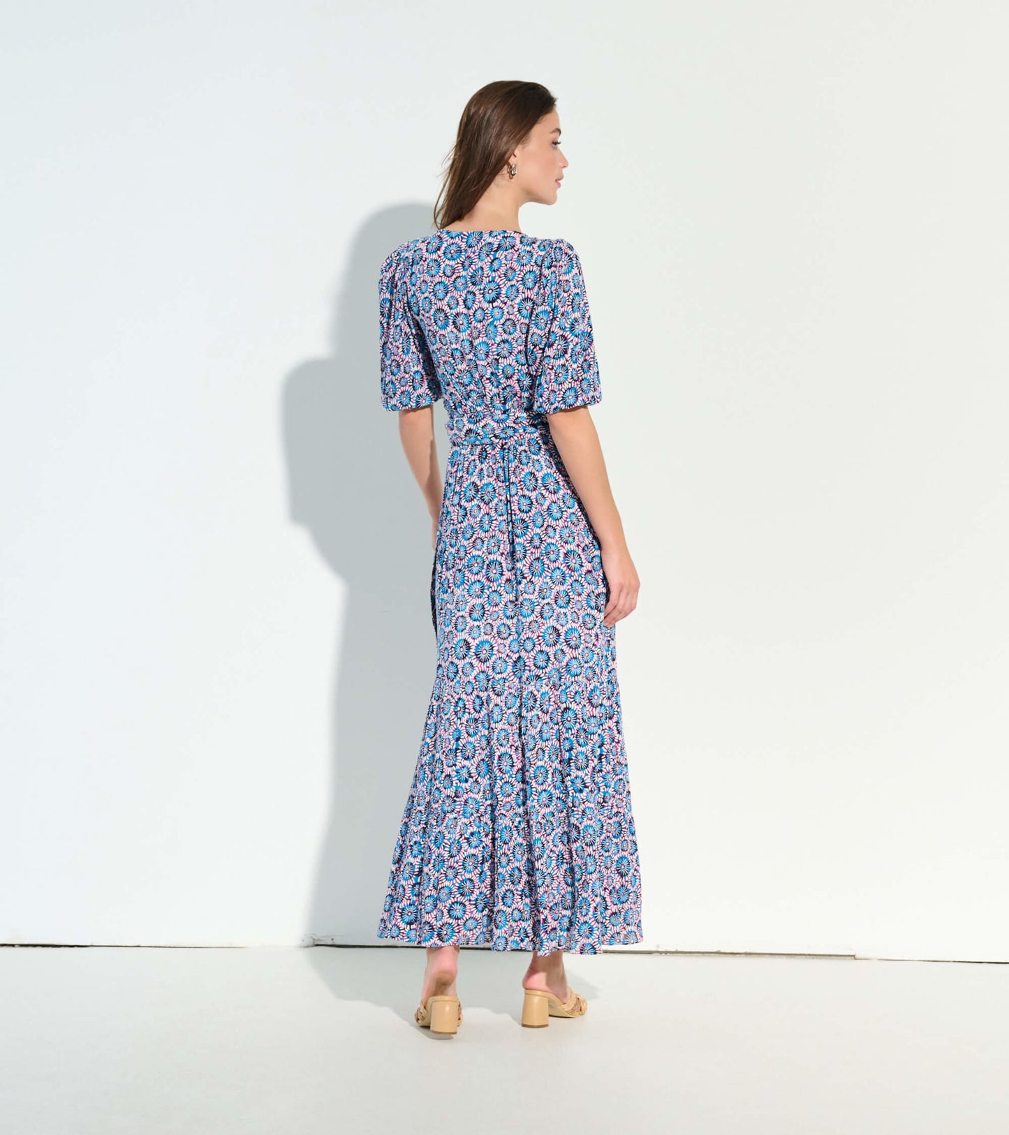 Back view of a long, flowy dress featuring a colorful sundial mandala pattern and short puff sleeves.