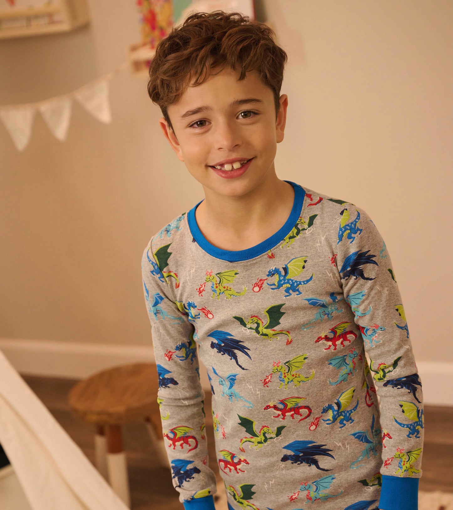 Gray long-sleeve pajama top featuring colorful dragon prints and blue trim, worn by a smiling boy.