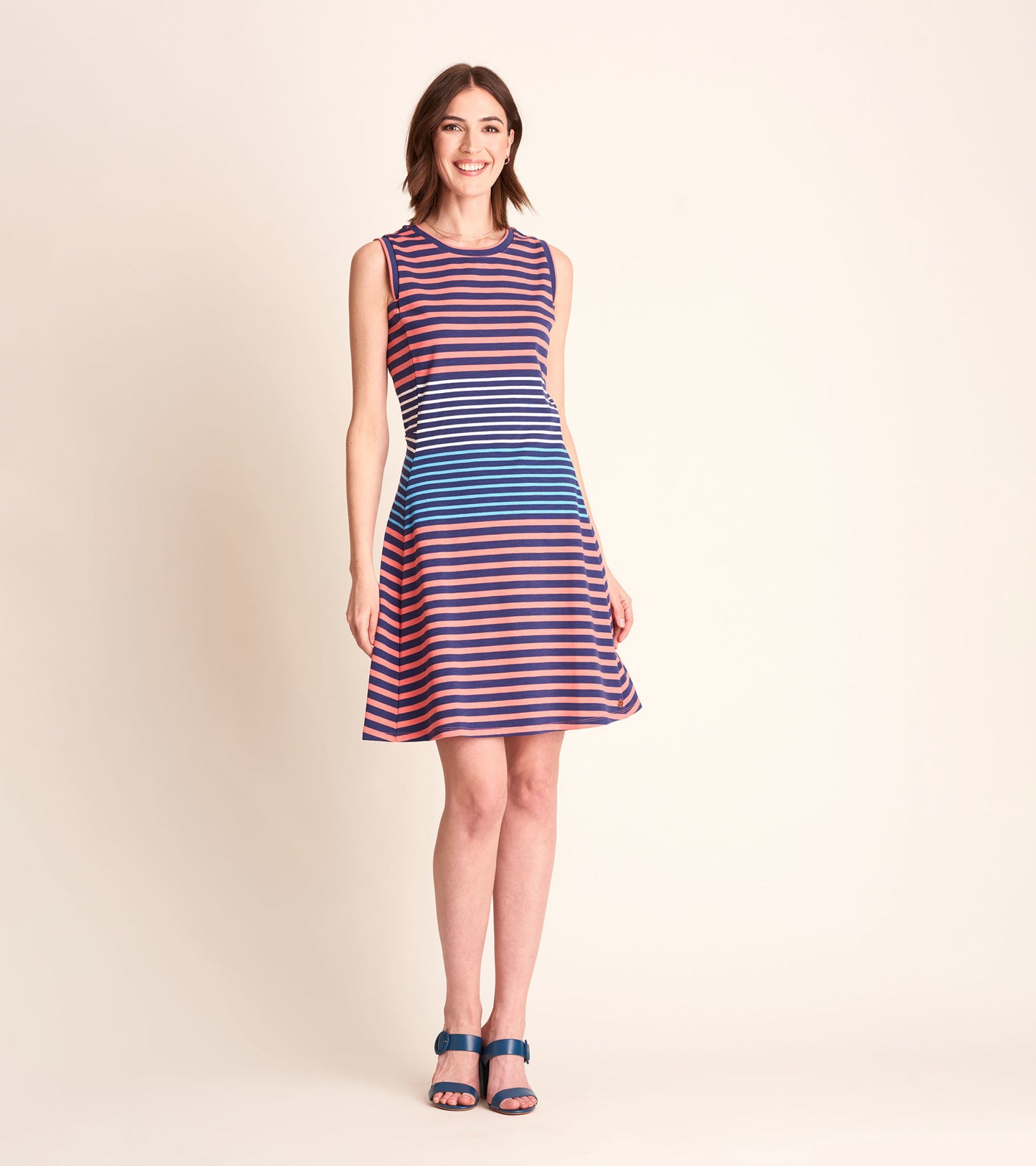 Sleeveless dress featuring navy and coral stripes, flared skirt, and a round neckline, styled with blue sandals.