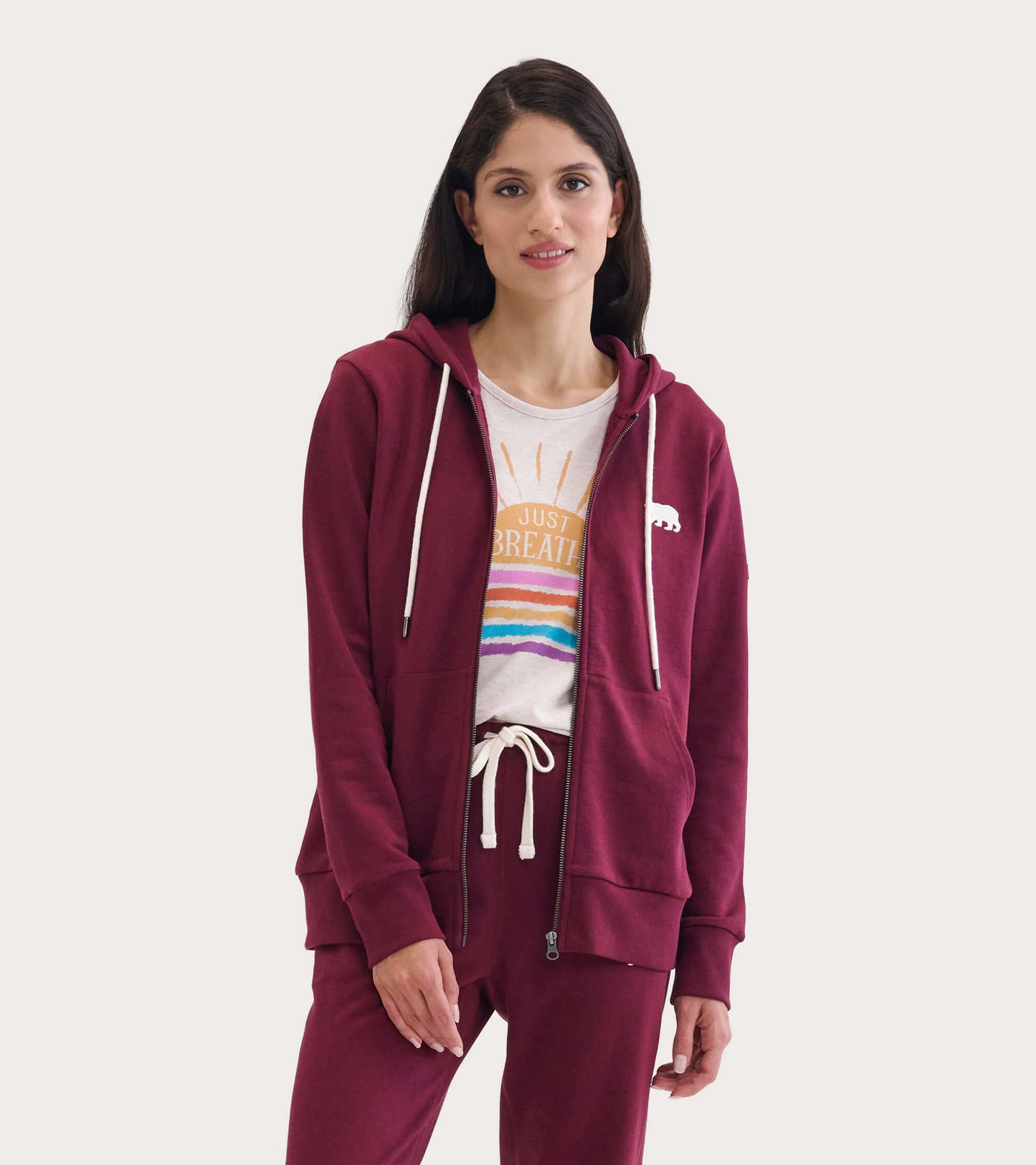 Maroon full zip hoodie with drawstring, featuring a bear logo, worn over a light graphic tee and matching pants.