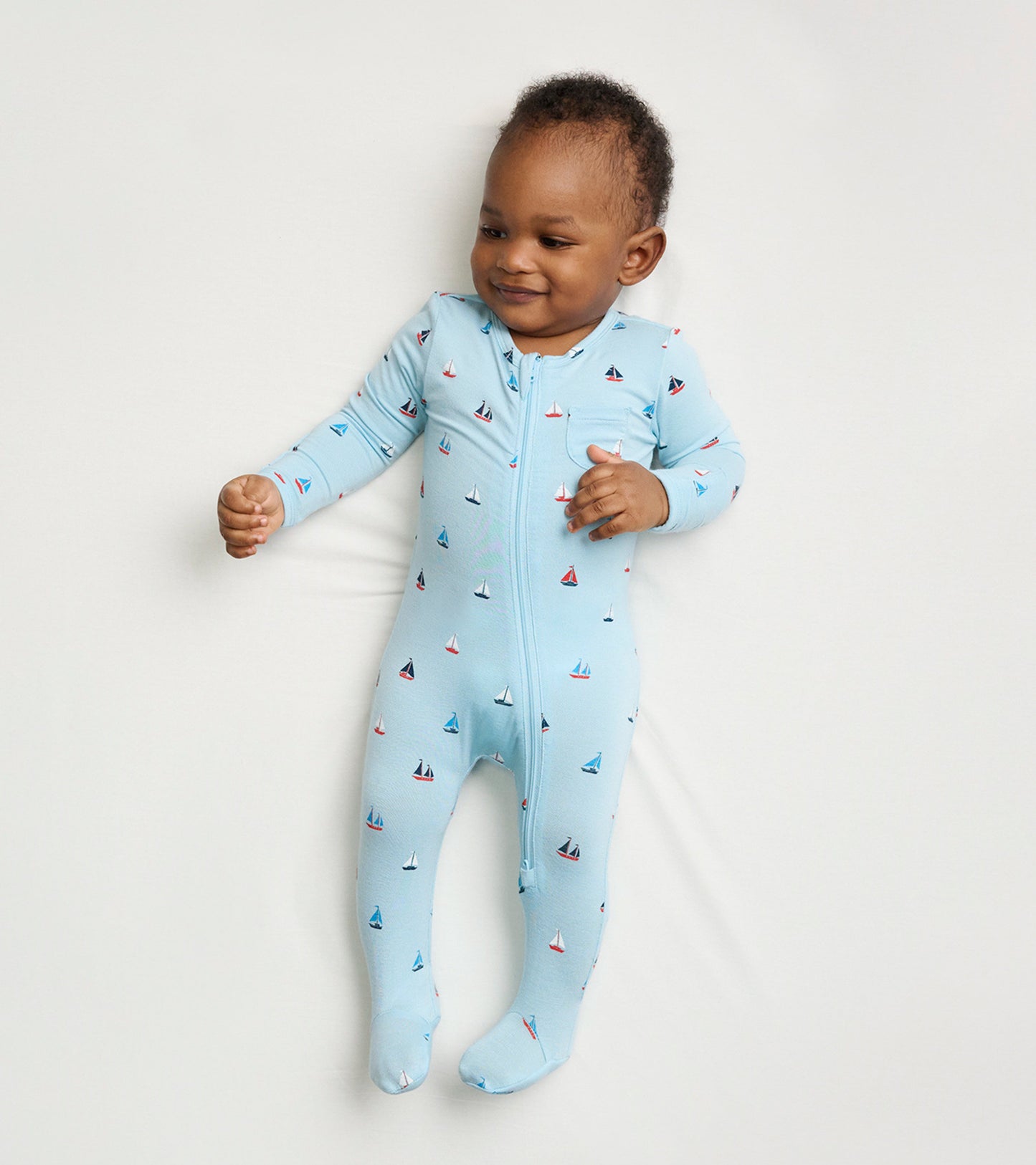 Light blue footed sleeper featuring a sailboat pattern, designed for baby boys, with a front zipper for easy dressing.