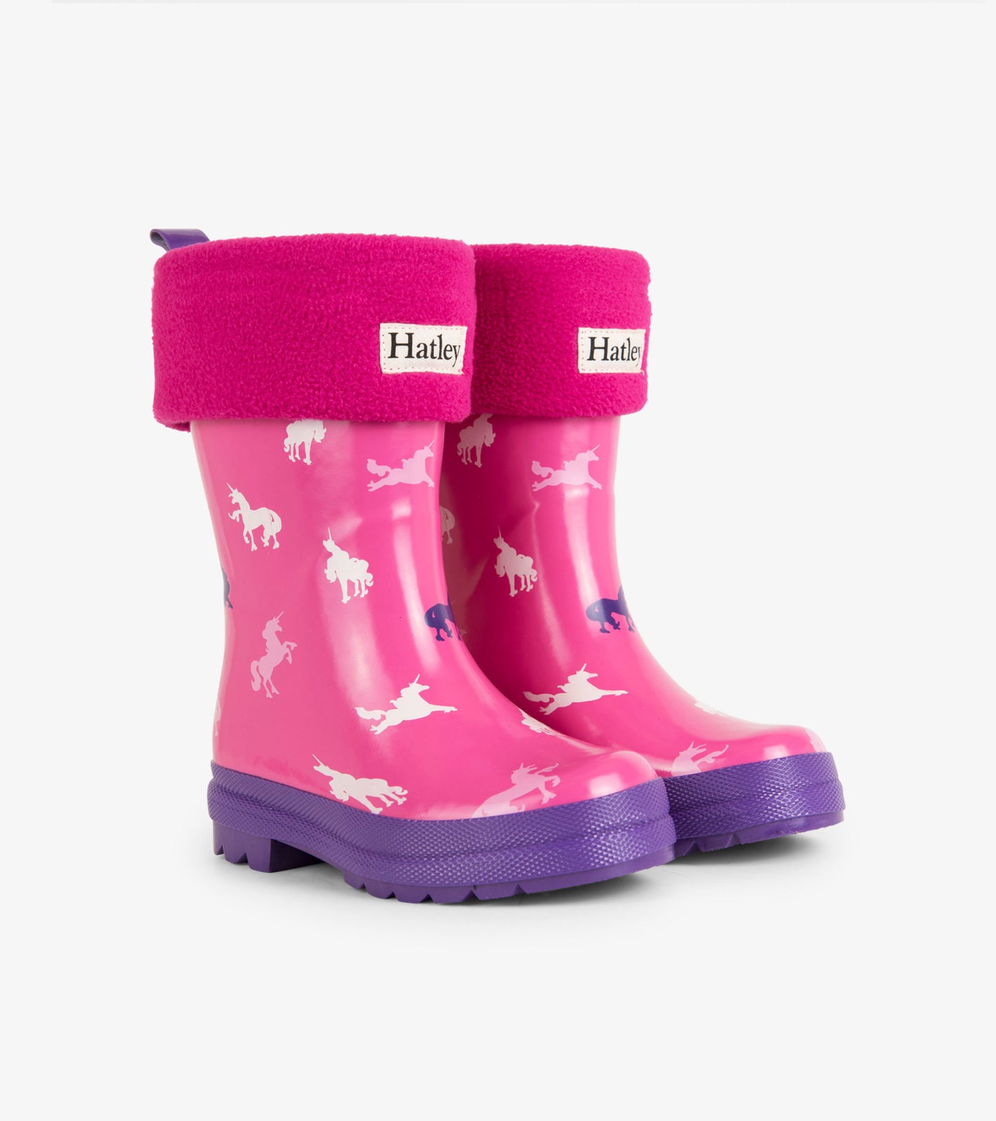 Magenta kids' rain boots with unicorn patterns and purple soles, featuring a soft pink fleece cuff.