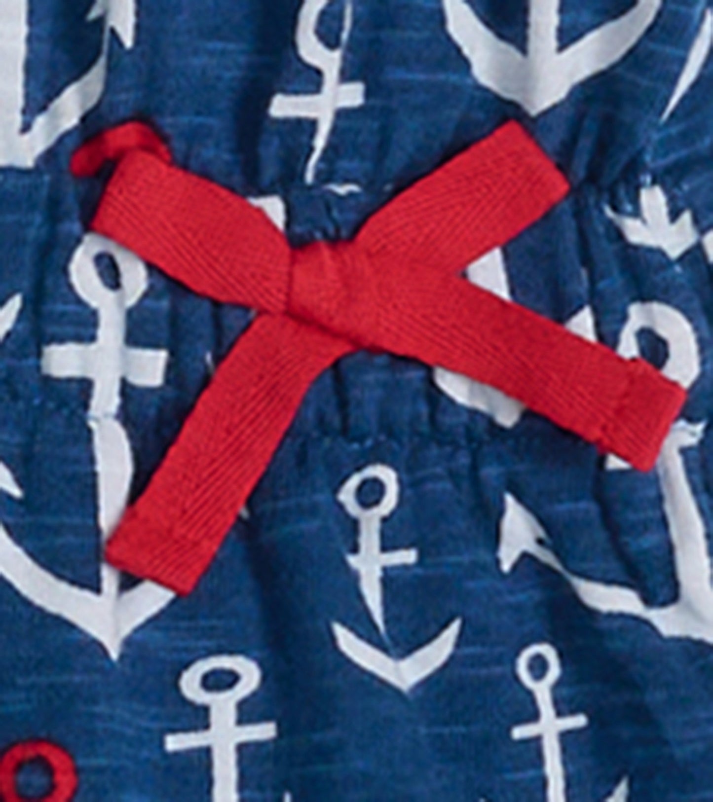 Navy t-shirt dress featuring white anchor patterns and a red bow detail at the waist.