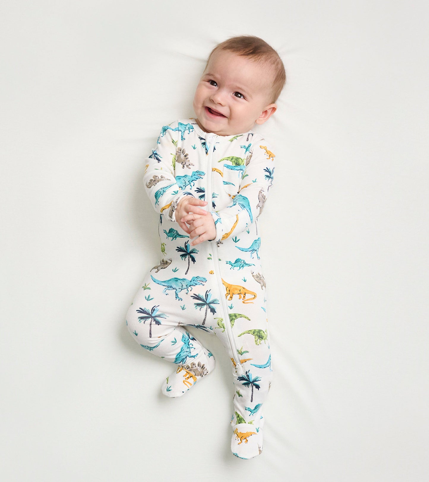 Footed sleeper for baby boys featuring a colorful dinosaur print on a light background, designed for comfort and warmth.