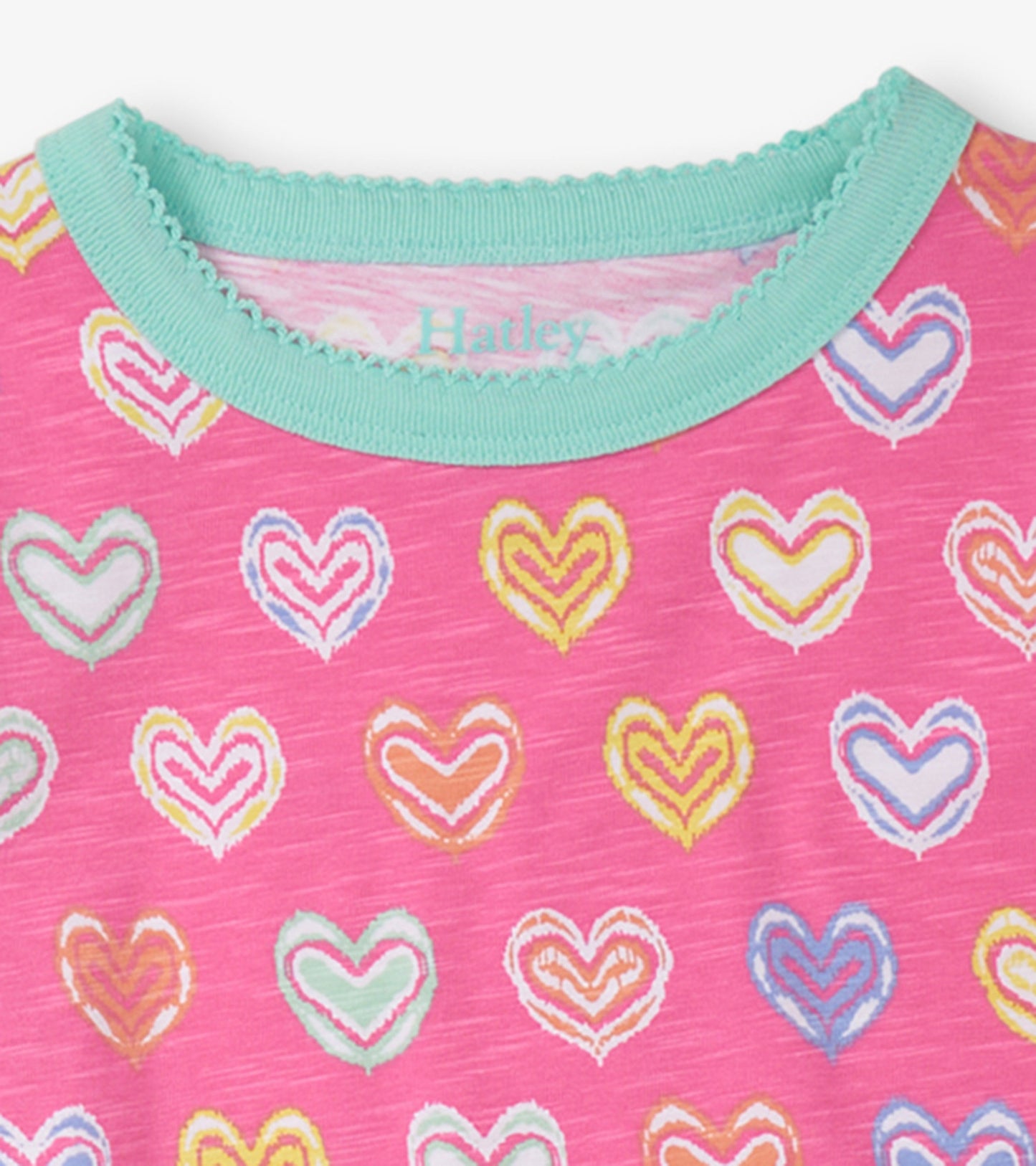 Pink short pajama top featuring colorful shibori heart patterns and a turquoise scalloped neckline.