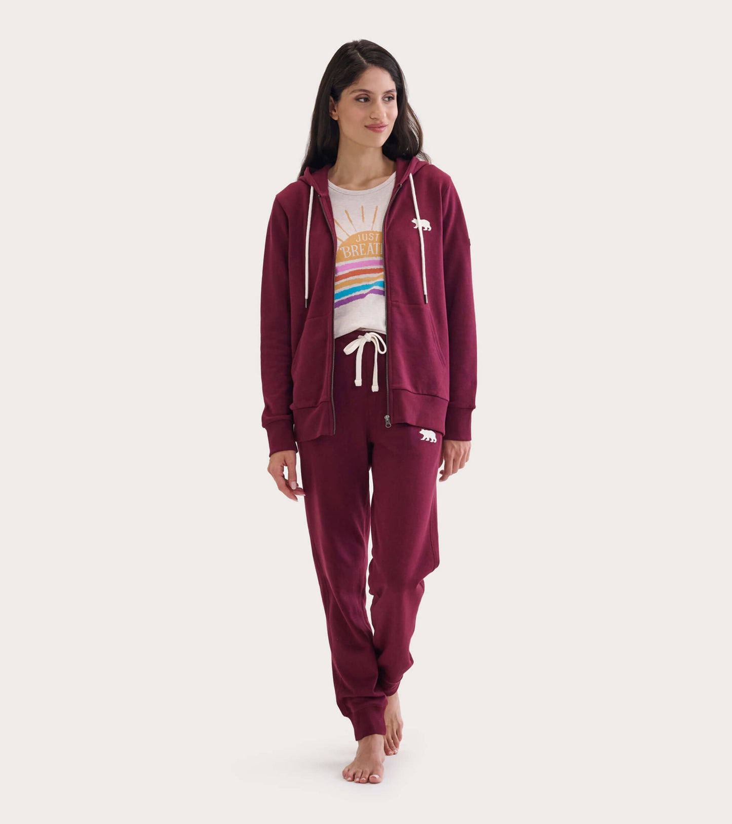Maroon full zip hoodie with a relaxed fit, featuring a drawstring hood and side pockets, worn over a graphic tee and matchin…