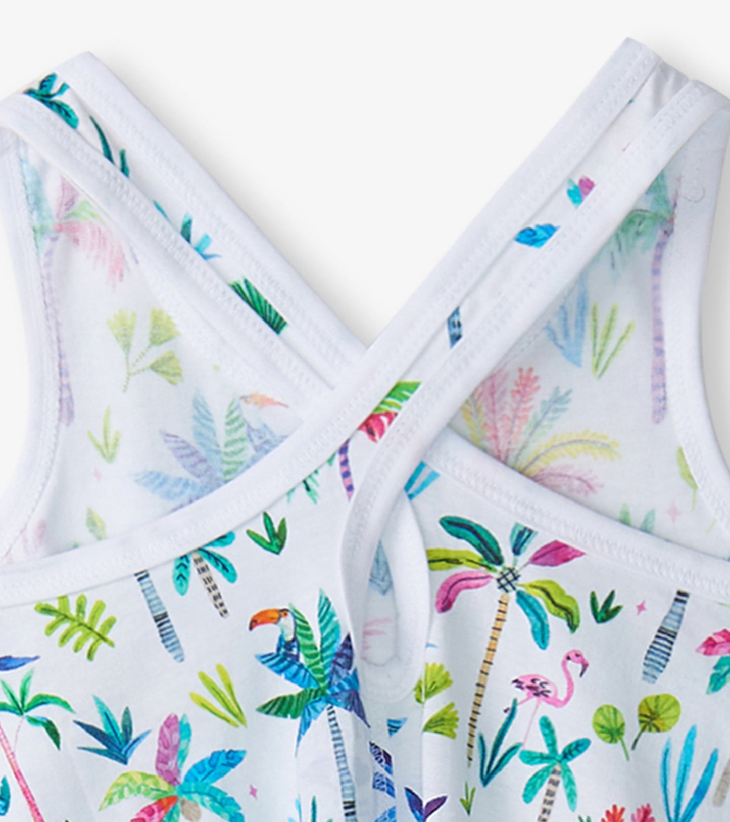 White trapeze dress featuring a colorful tropical palm and flamingo print with crisscross straps.
