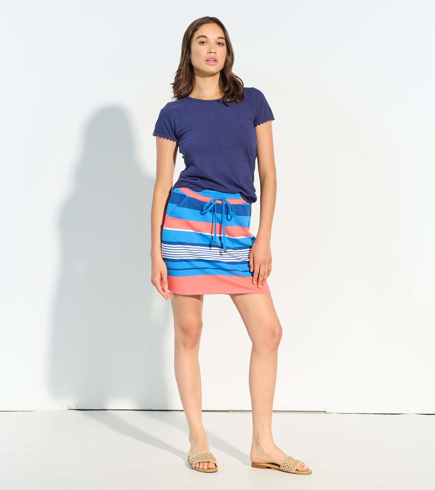 Striped skirt in blue, pink, and white with a drawstring waist, styled with a navy top and sandals.