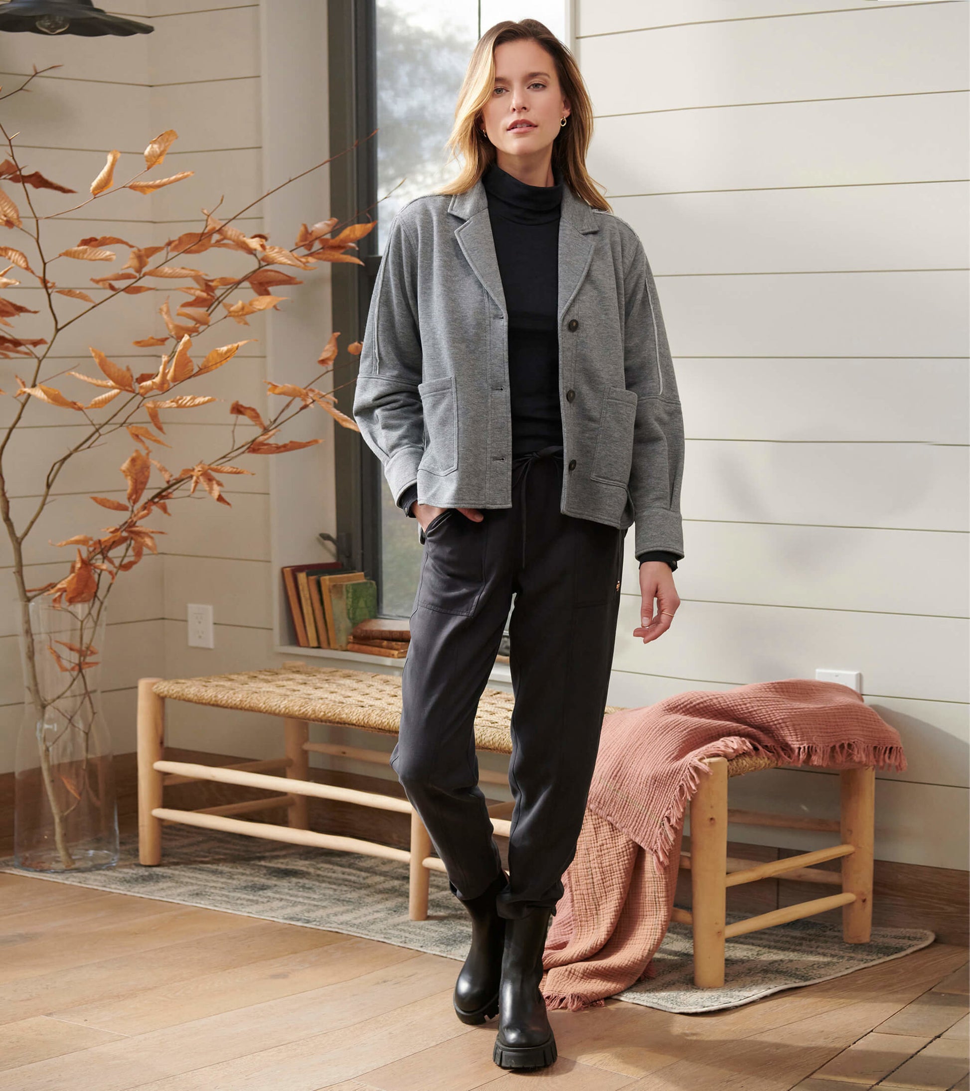 Charcoal melange relaxed blazer with a button front, paired with black pants and ankle boots, styled in a cozy indoor settin…