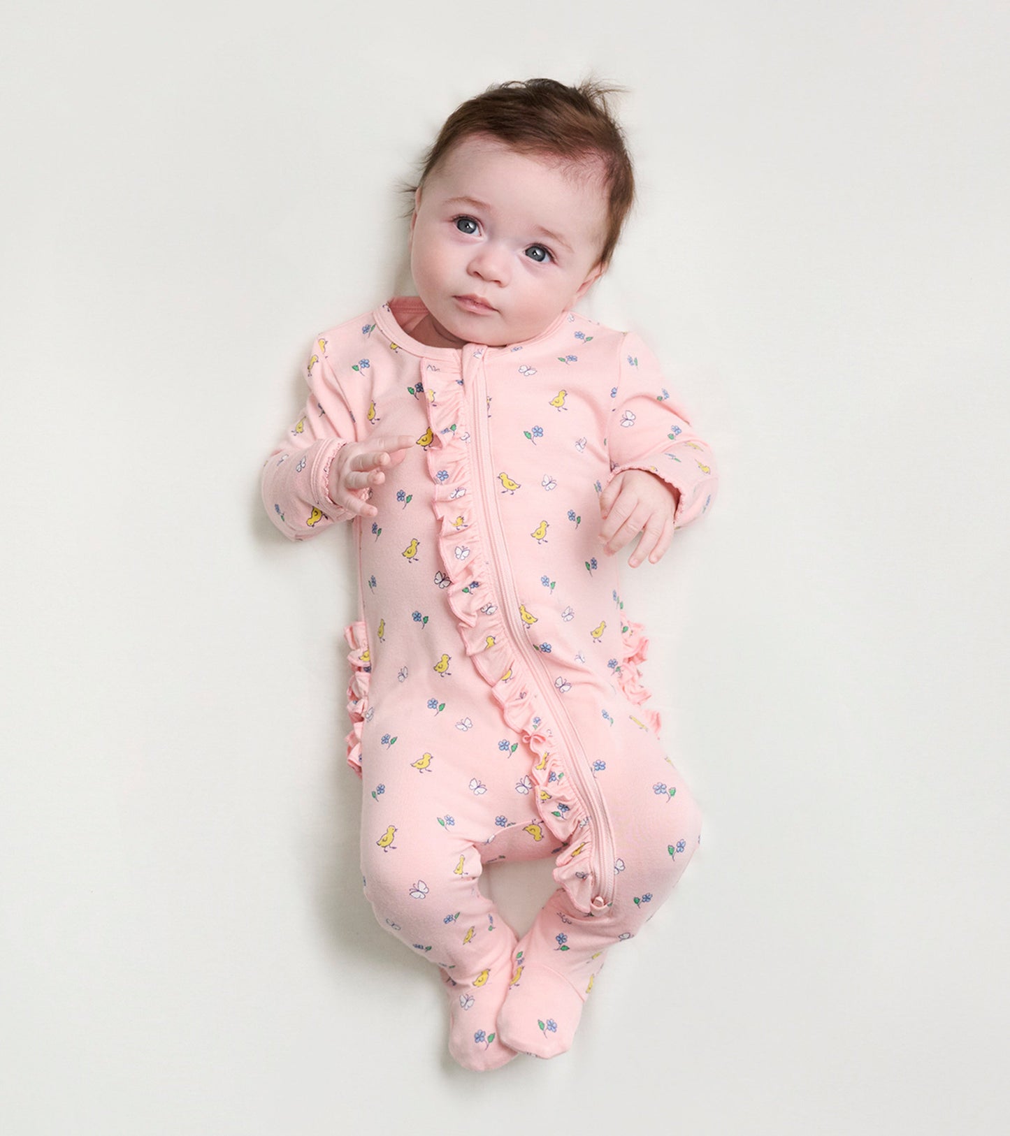 Pink footed sleeper with ruffles, featuring a floral and duckling pattern, designed for baby girls.