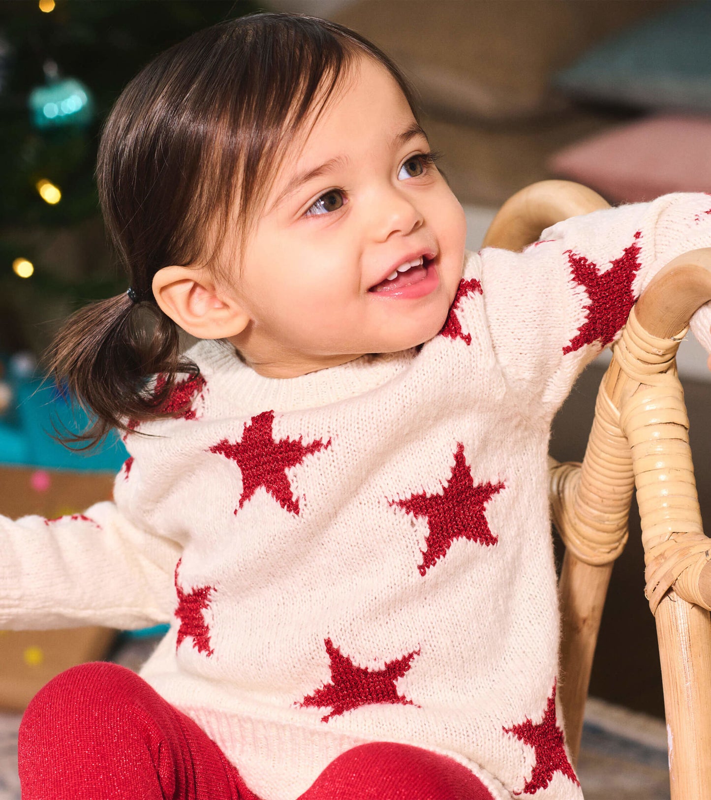 Cream sweater dress with red star pattern, worn by a smiling child, paired with red leggings.