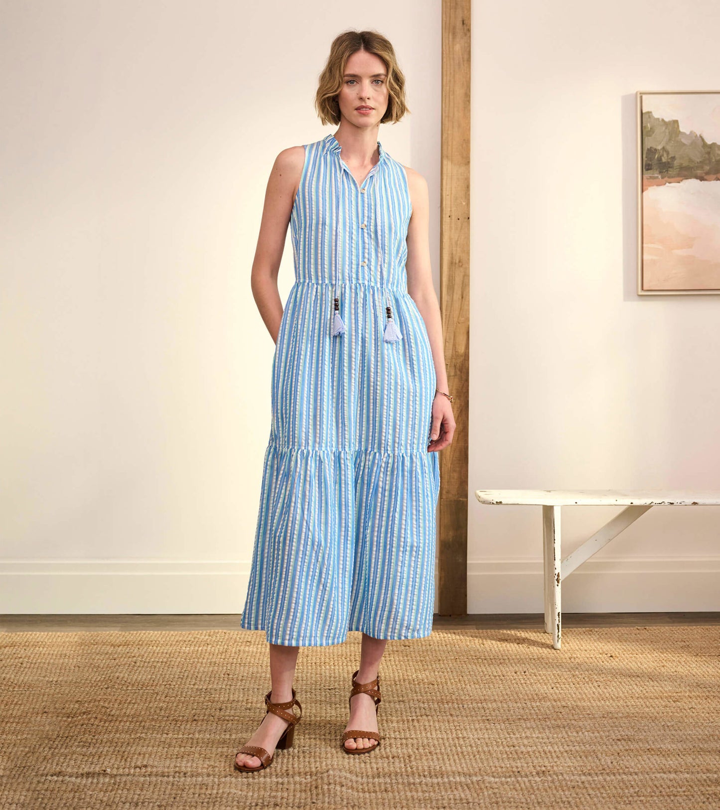 Light blue seersucker sundress with vertical stripes, button front, and tiered skirt, styled with sandals.