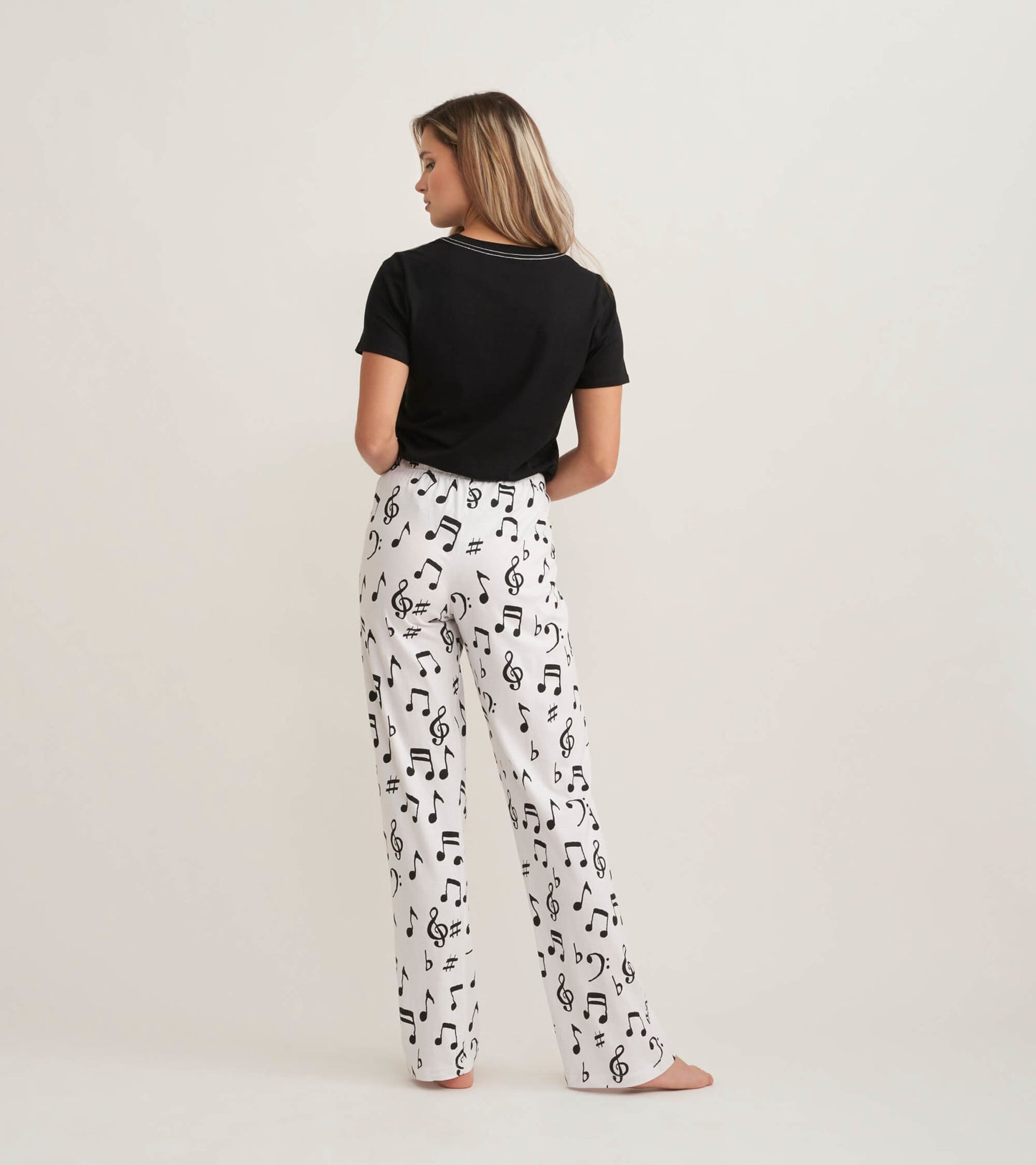 White cotton pajama pants with black musical notes, styled for a relaxed fit, shown from the back.