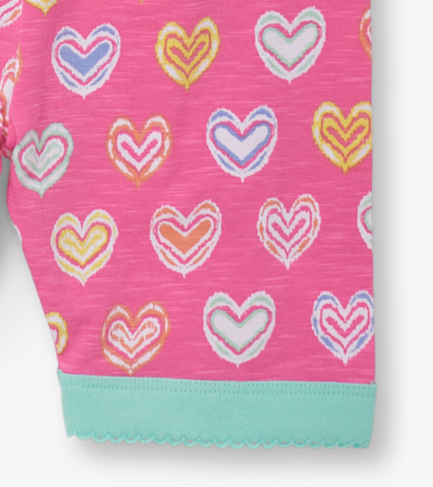 Pink short pajama set featuring colorful shibori heart patterns and a mint green trim at the hem.