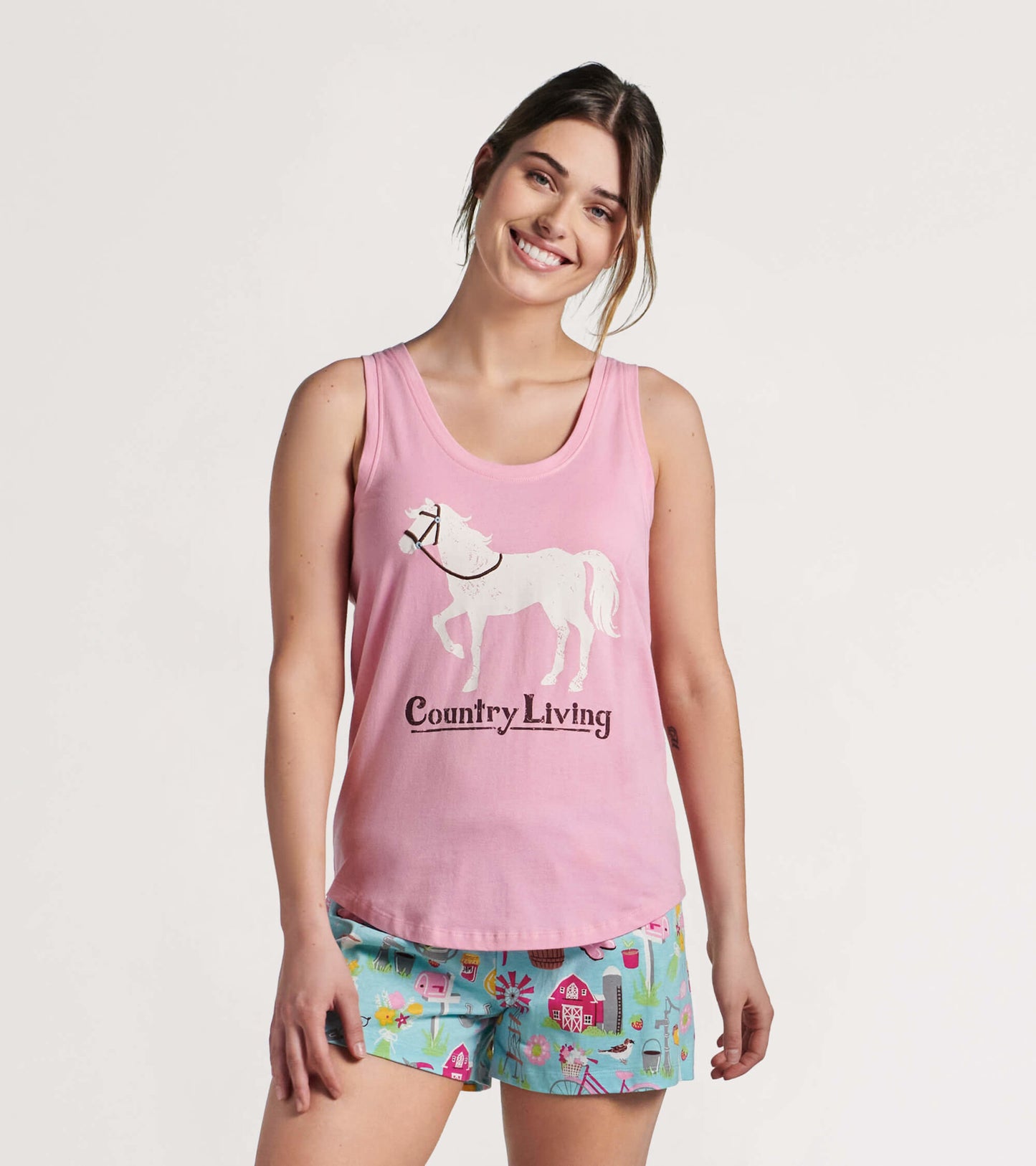 Pink tank top featuring a white horse graphic, paired with colorful patterned shorts. Ideal for casual lounging.